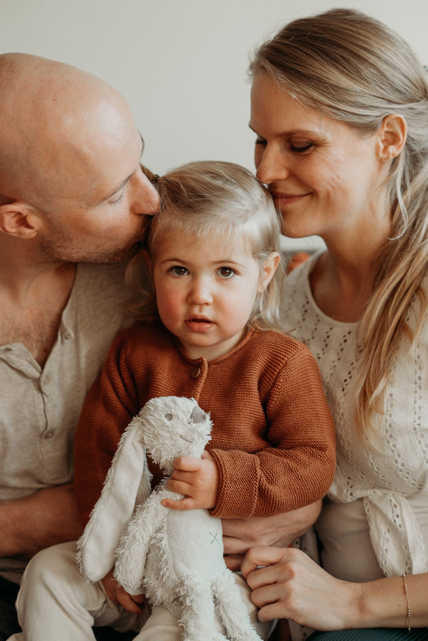Family moment with stuffed animal toy in warm neutral tones.