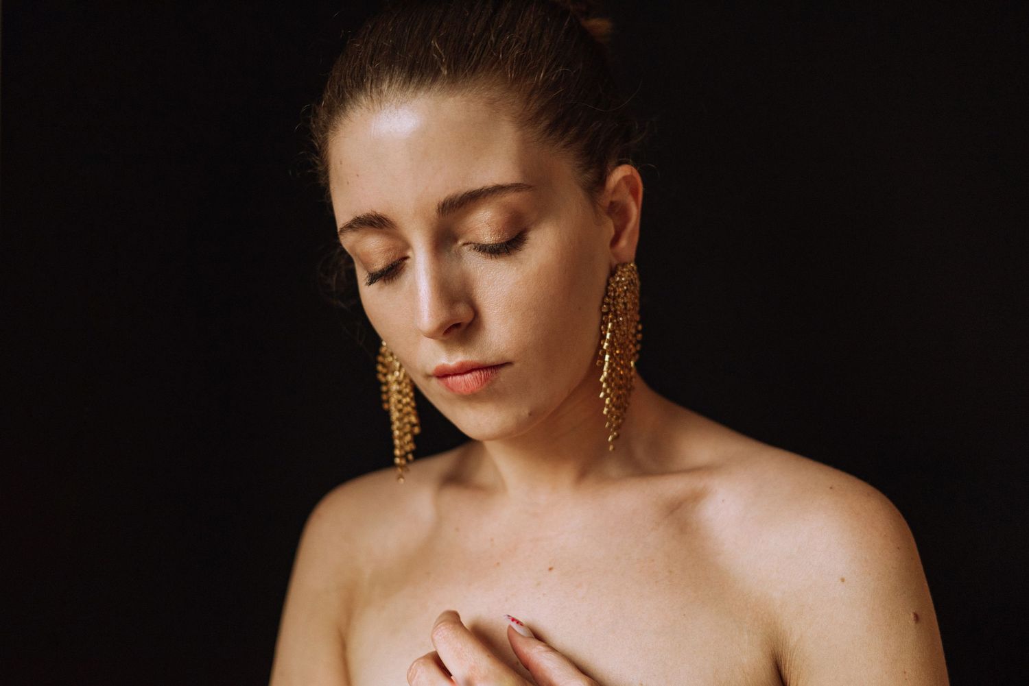 Dramatic black and white portraits with gold earrings against dark background.