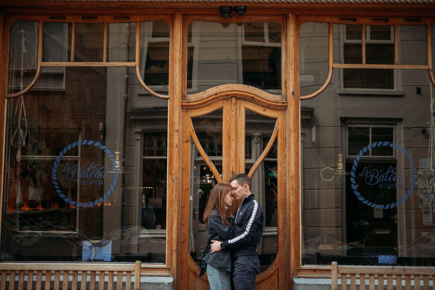 Historic storefronts with ornate wooden details and large windows along city street.