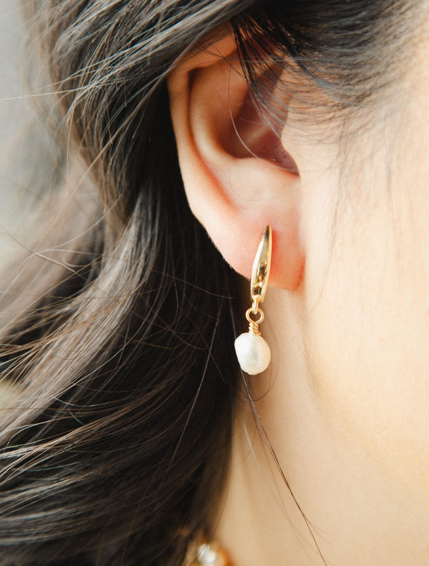 Close-up shots of gold drop earrings and jewelry worn on ear.