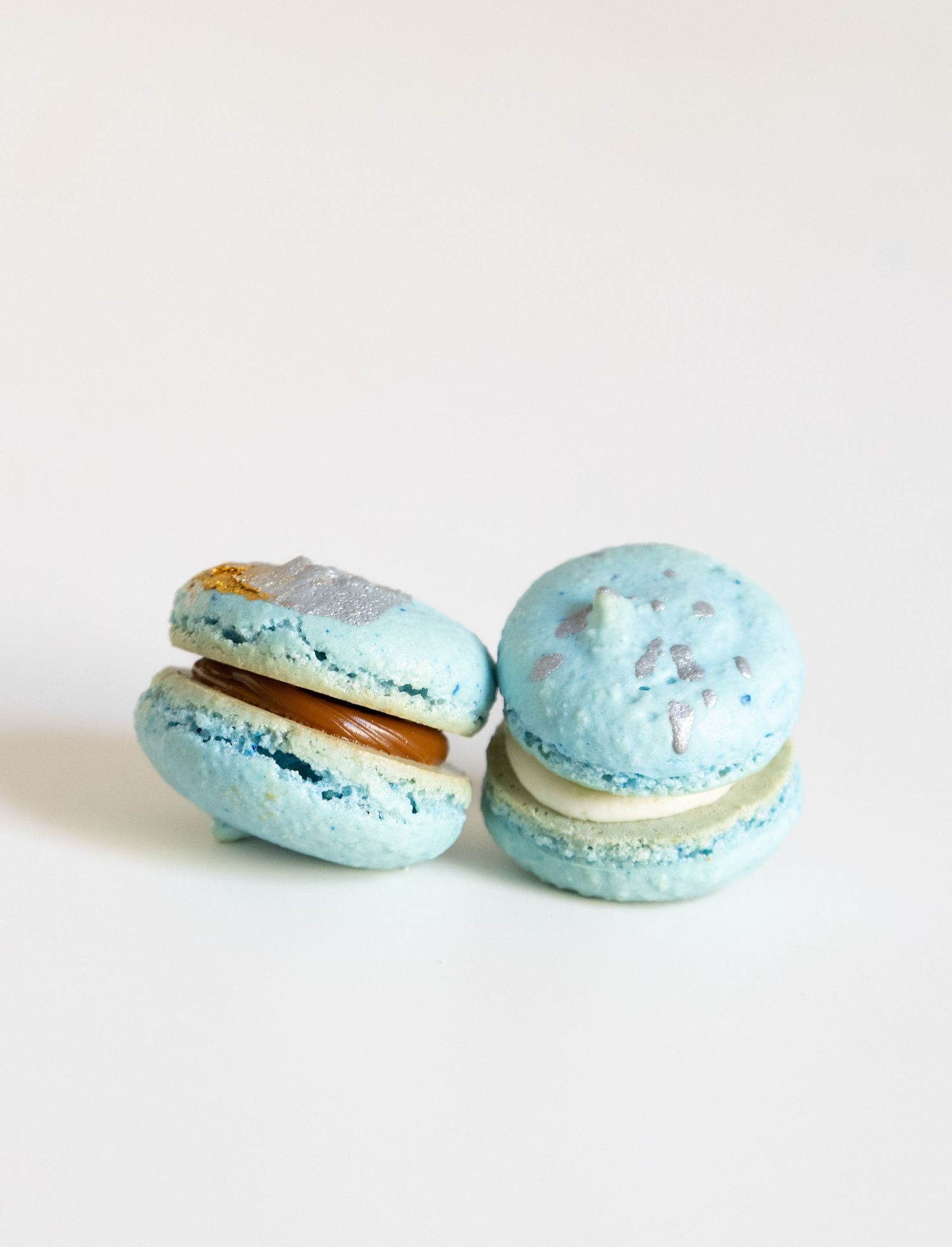 Light blue macarons with gold decorative accents shown in a progression of opening stages on white background.