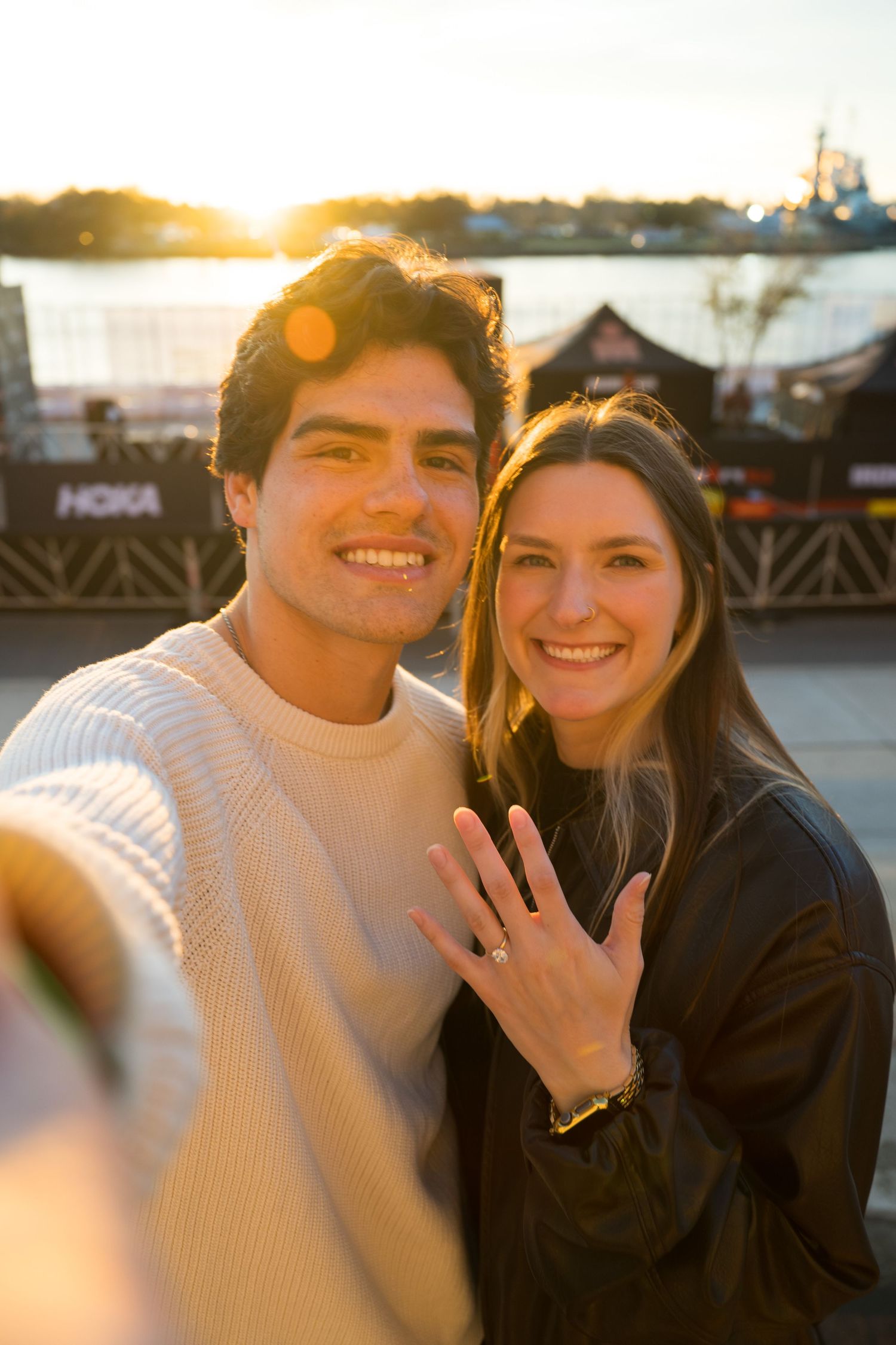 A couple poses together at sunset showing off an engagement ring in a series of romantic photos.