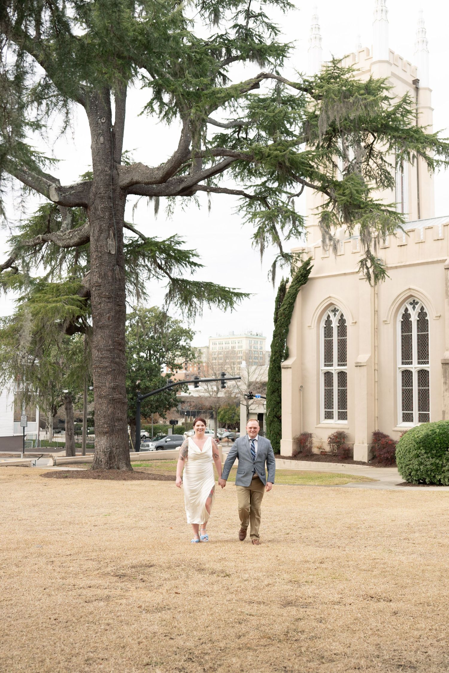 Beautiful historic church exterior with tall gothic windows and a large evergreen tree on the church grounds during autumn.