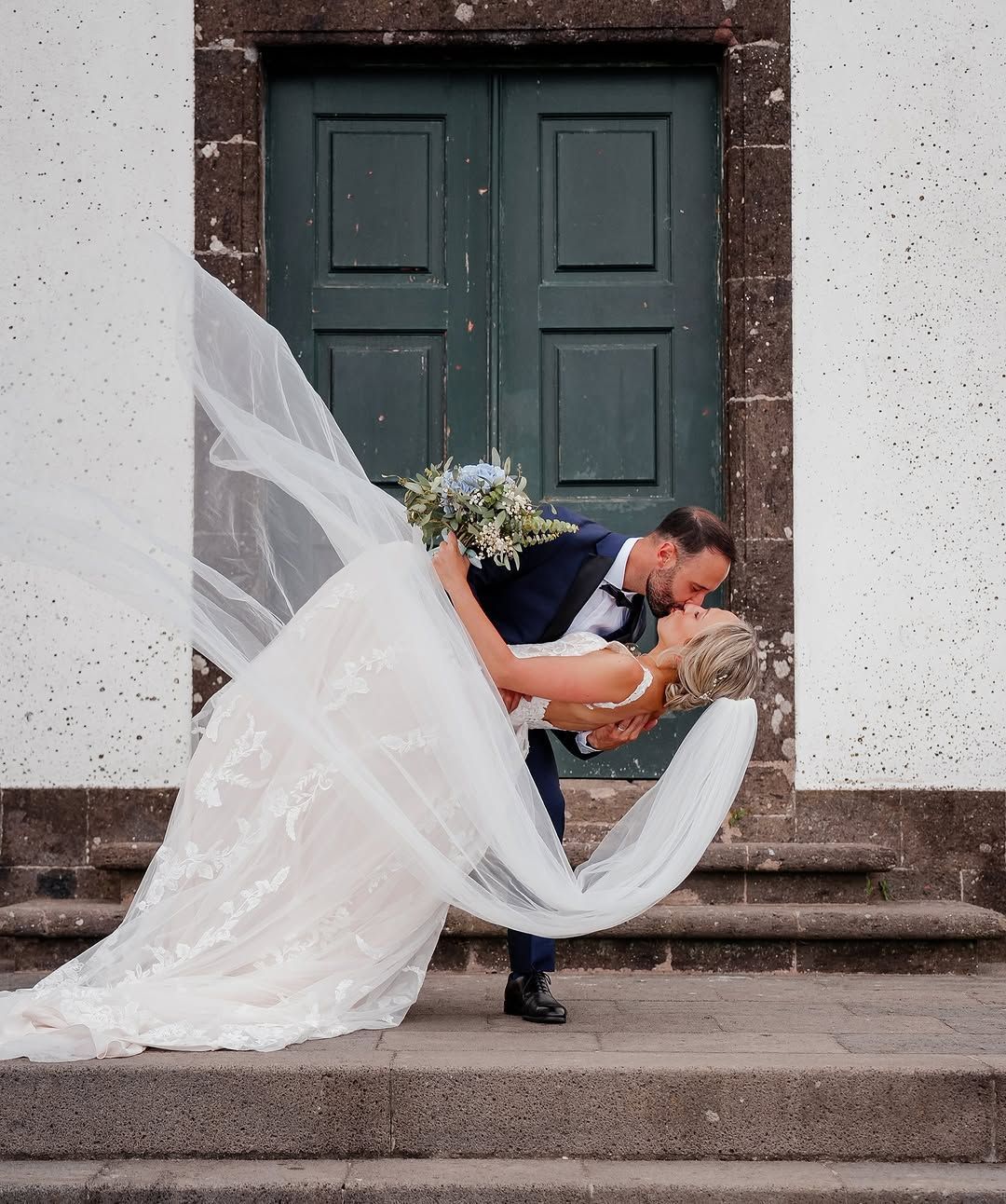 Groom lifting bride in front of green door – romantic wedding moment captured in the Azores