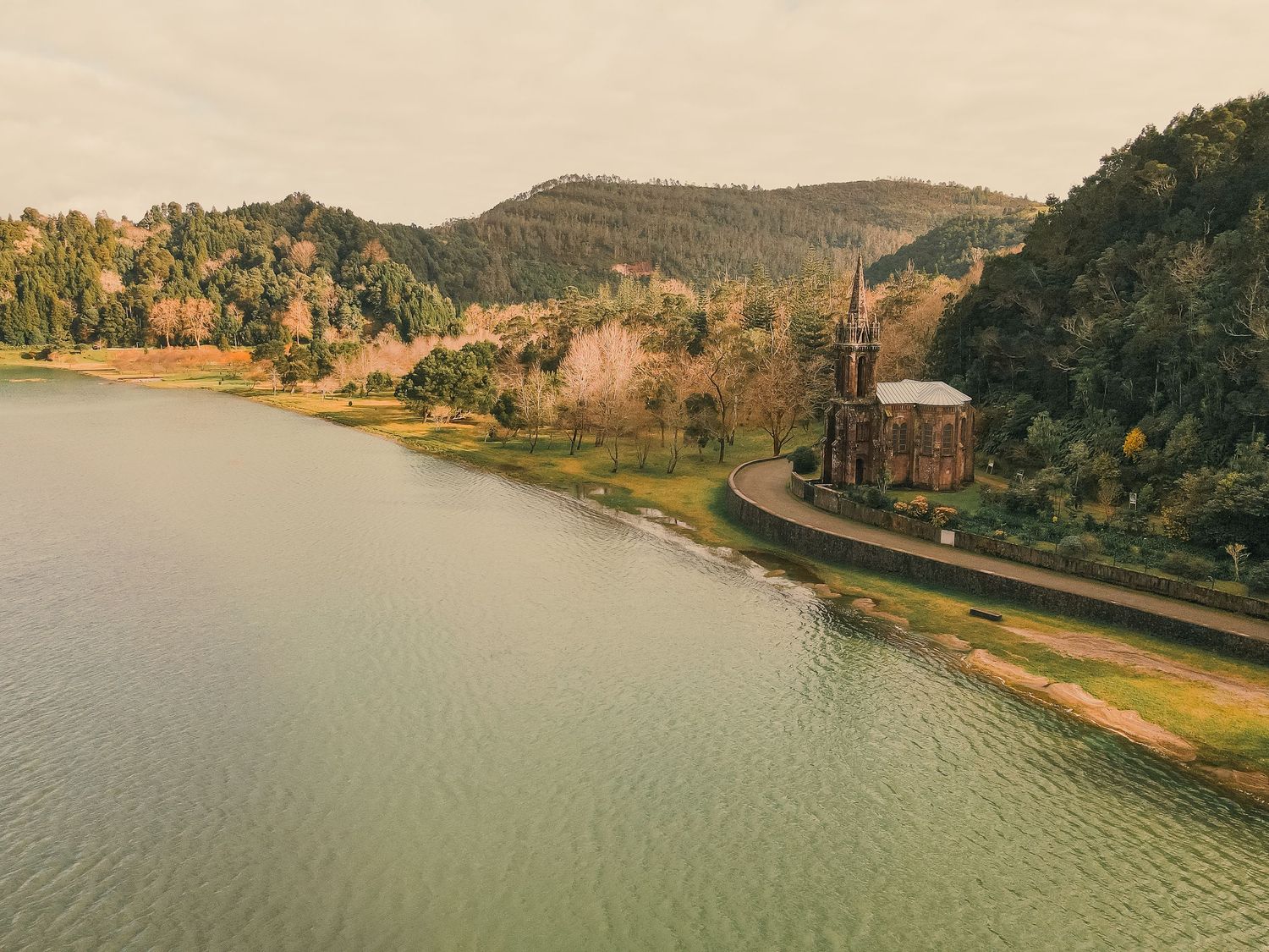 Aerial view of a winding river snaking through green hills with a road running alongside the waterfront.