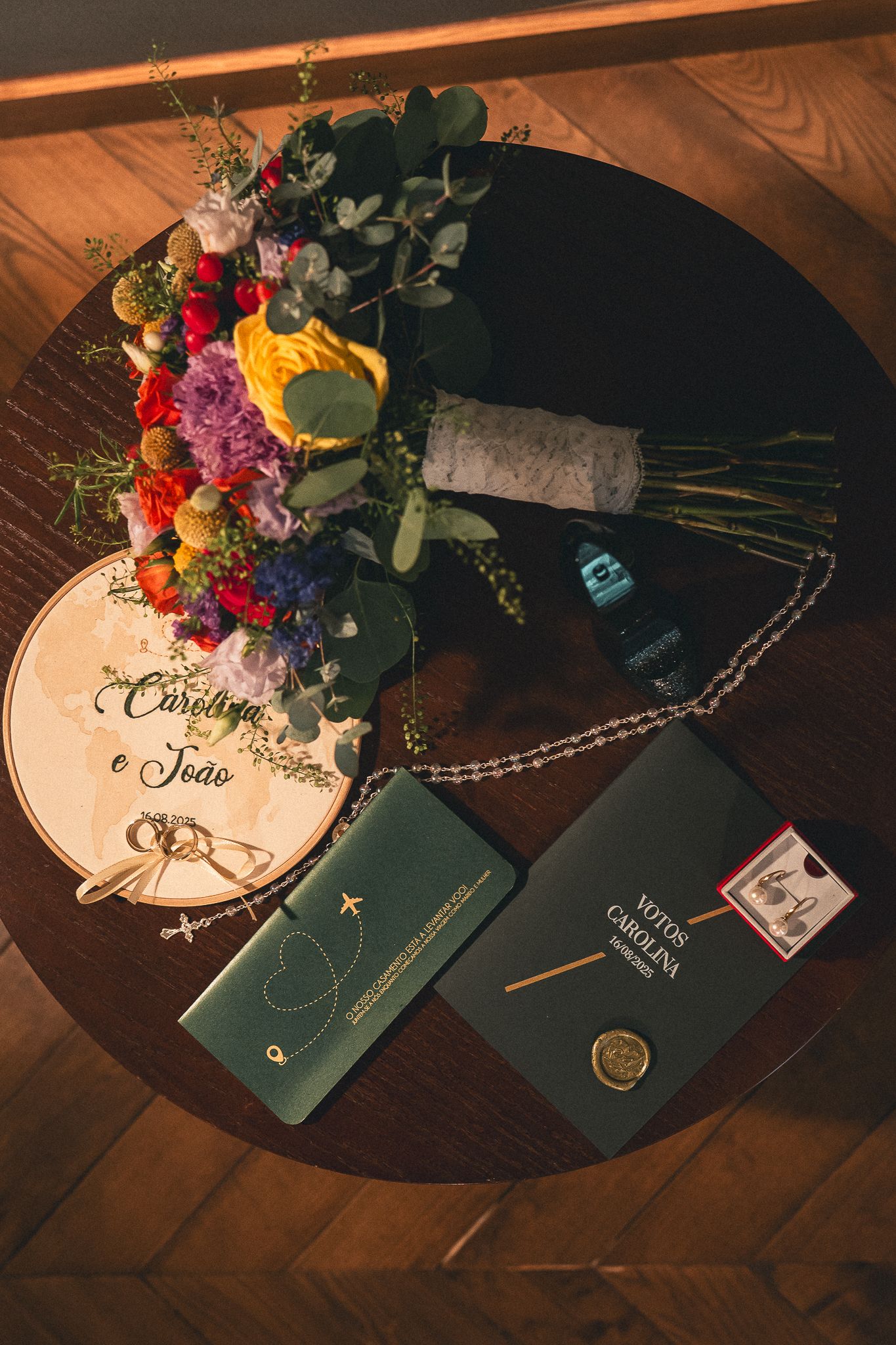Wedding invitation suite with blue passports, floral arrangement, and calligraphy details on dark wooden surface.