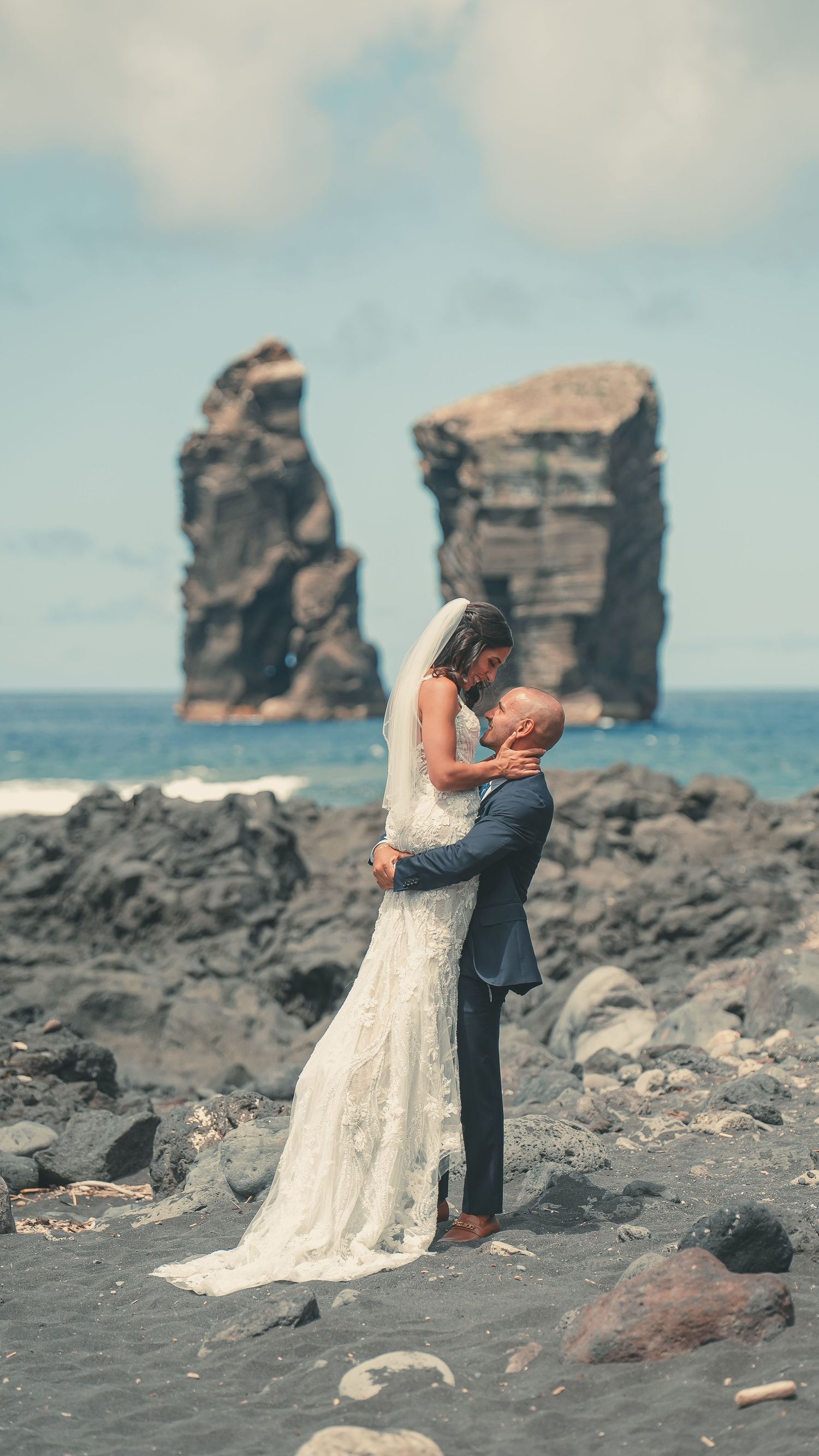 Bride standing on volcanic rocks of Mosteiros with ocean backdrop – wild Azores wedding by São Miguel photographer