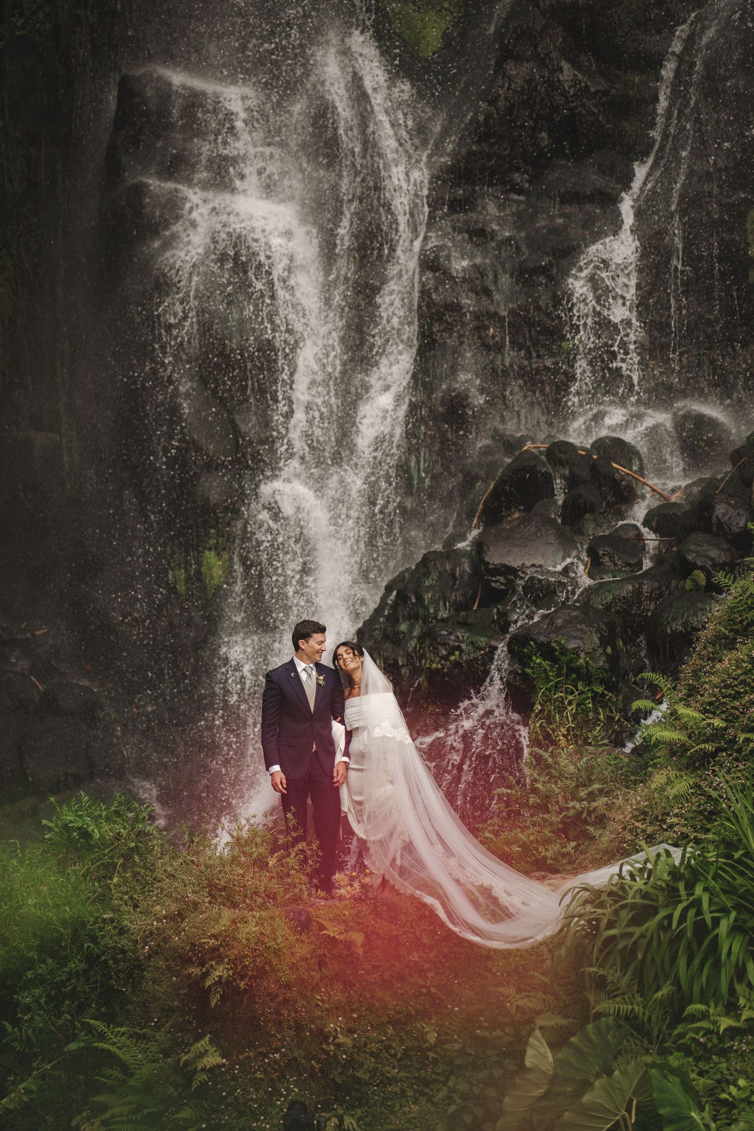 Couple standing under a lush Azorean waterfall — cinematic elopement captured by Azores wedding photographer in São Miguel