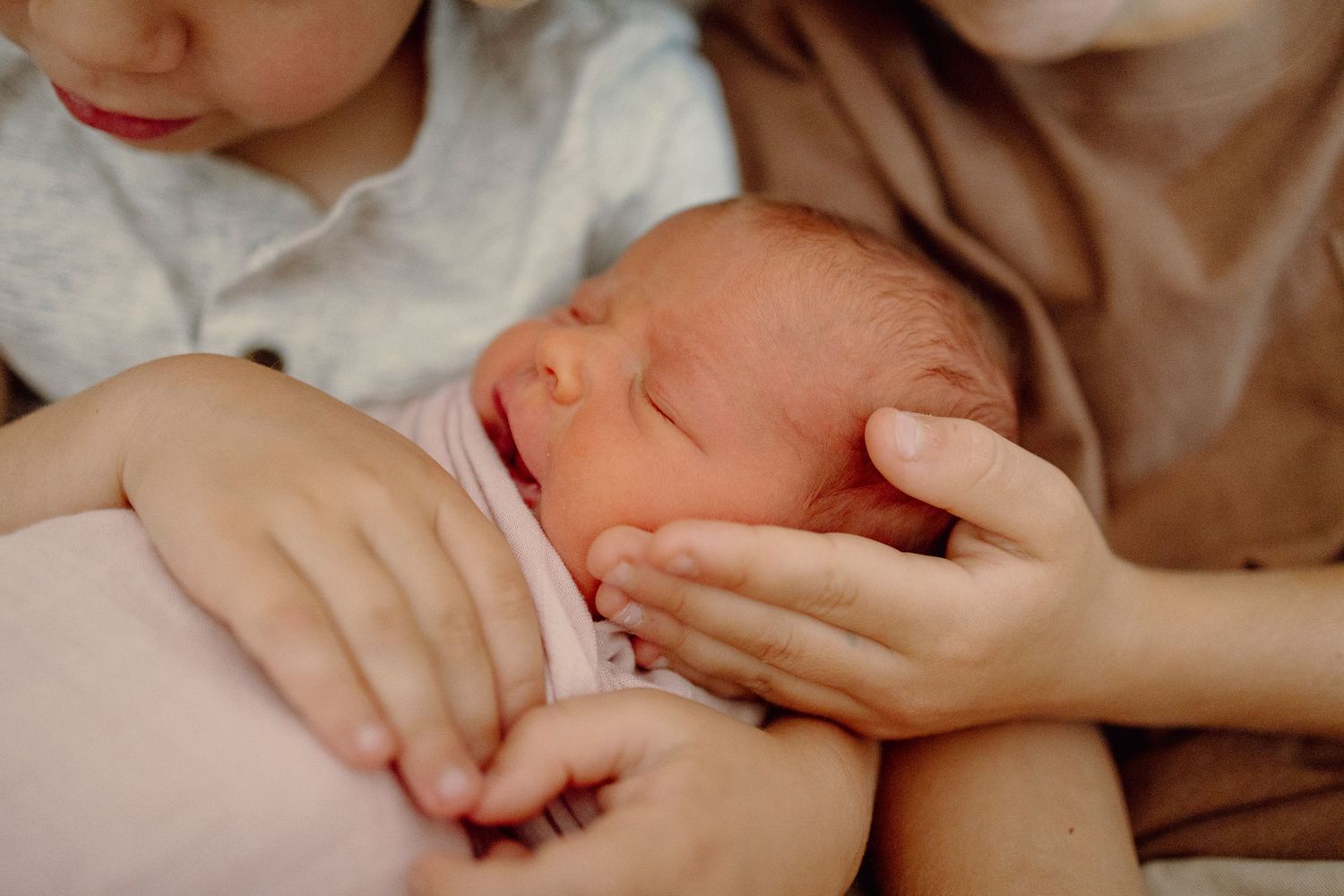 Close-up view of hands holding and examining a small baby's tiny fingers.