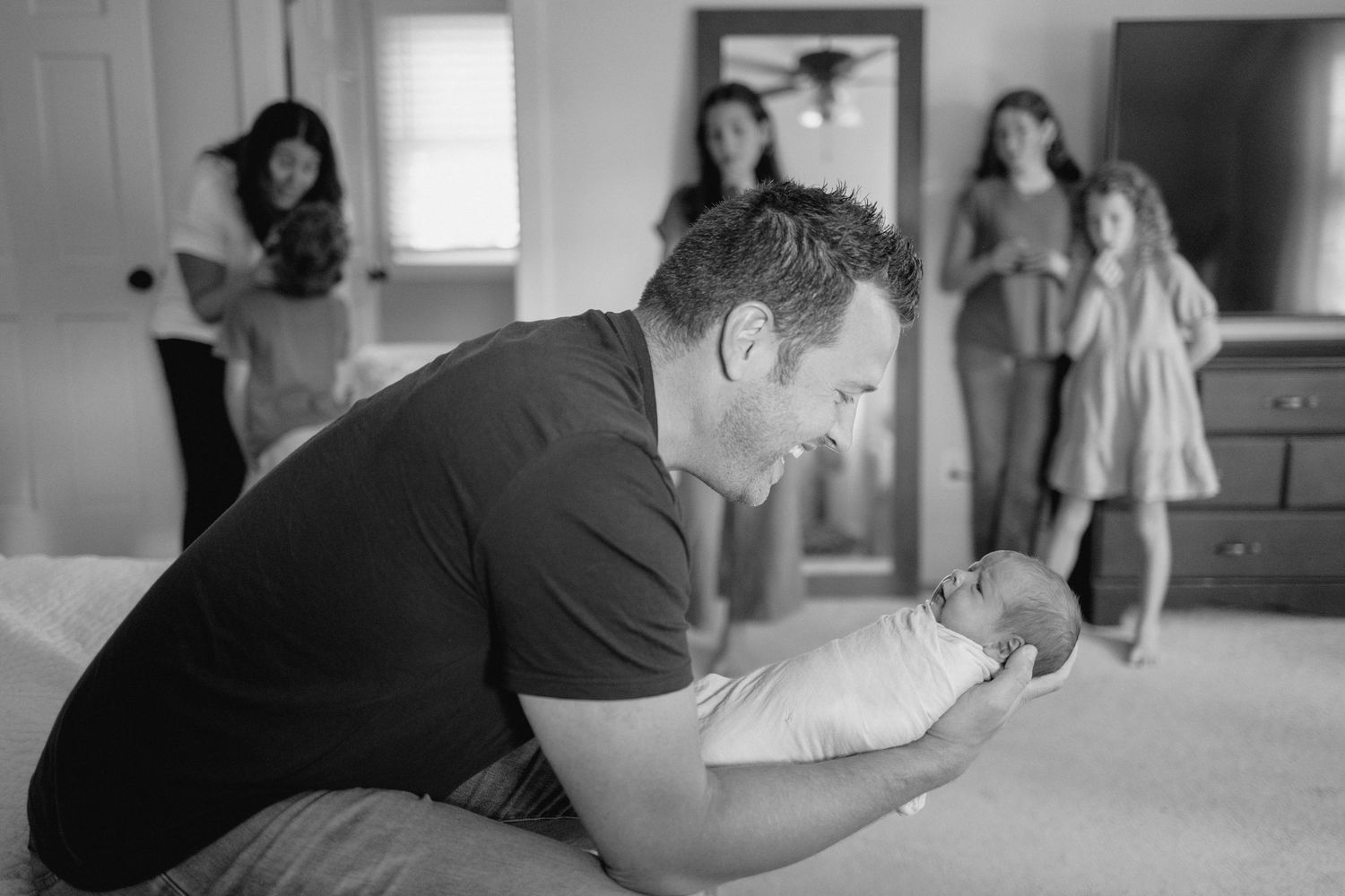 Black and white photo of a baby being gently cradled by daddy.