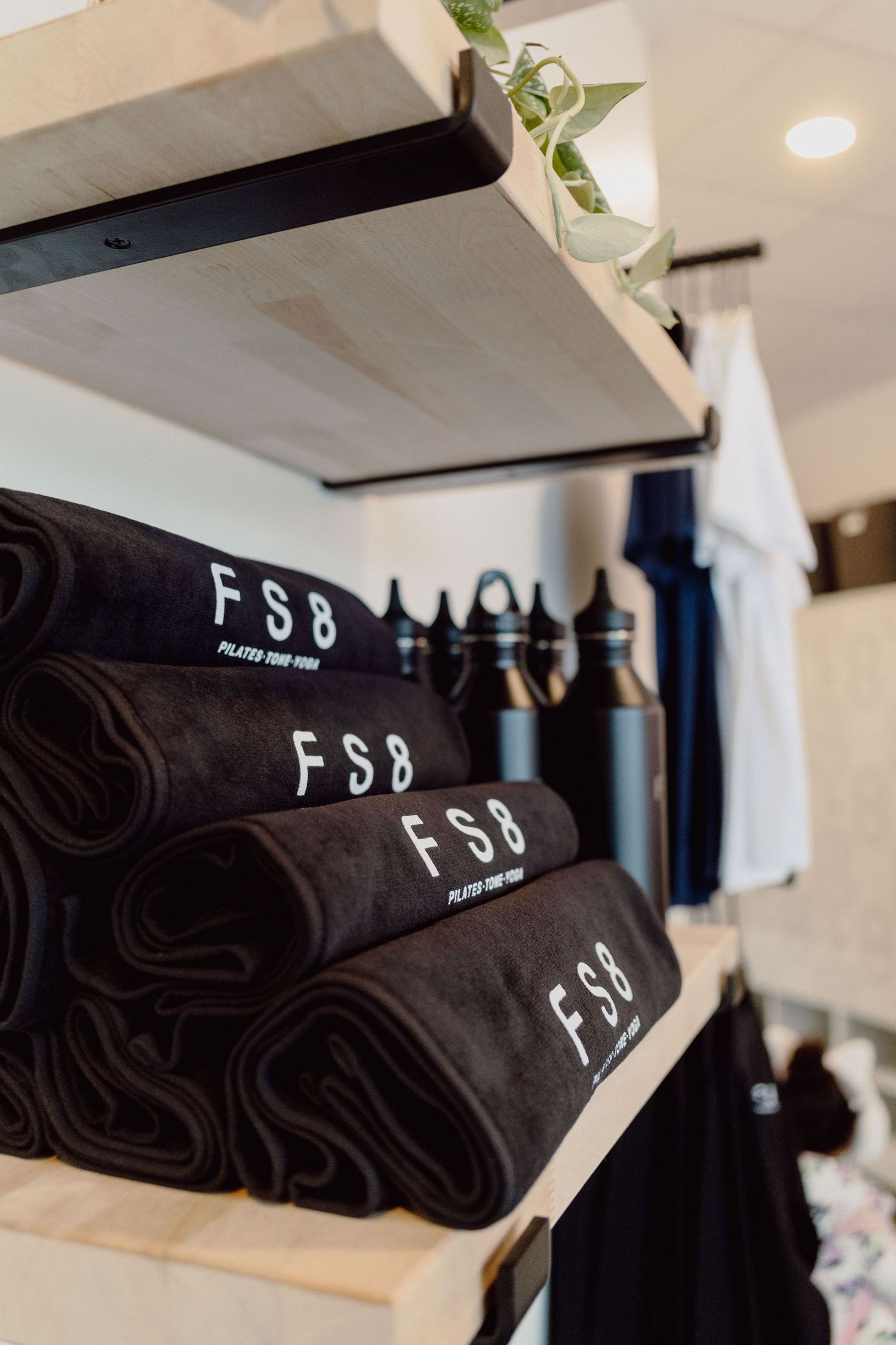 Black t-shirts with FSB logo text stacked neatly on retail display shelves in a modern boutique setting.