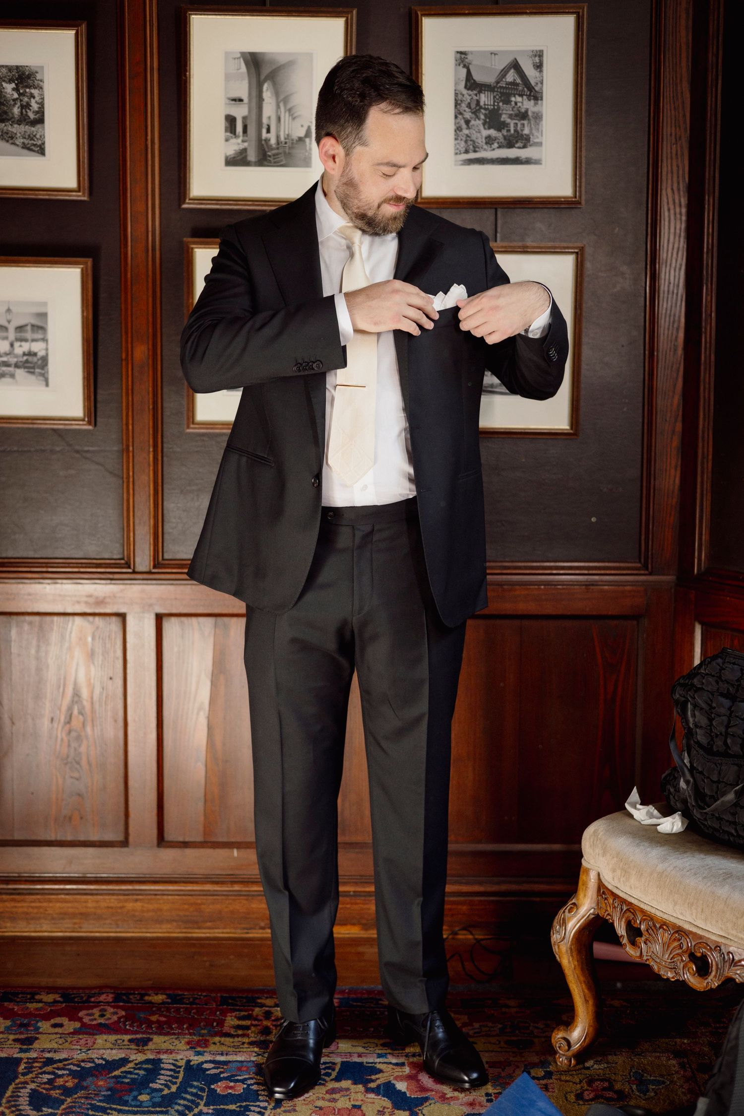 Getting ready sequence of adjusting formal black tie and bowtie against wood-paneled walls.