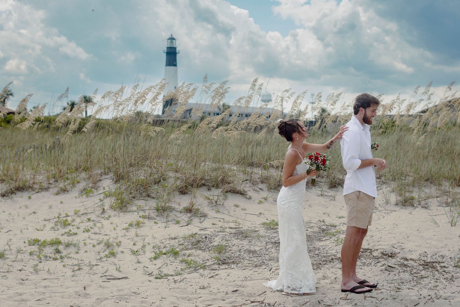 Beach wedding ceremony setup with white chairs on sandy dunes overlooking the ocean.