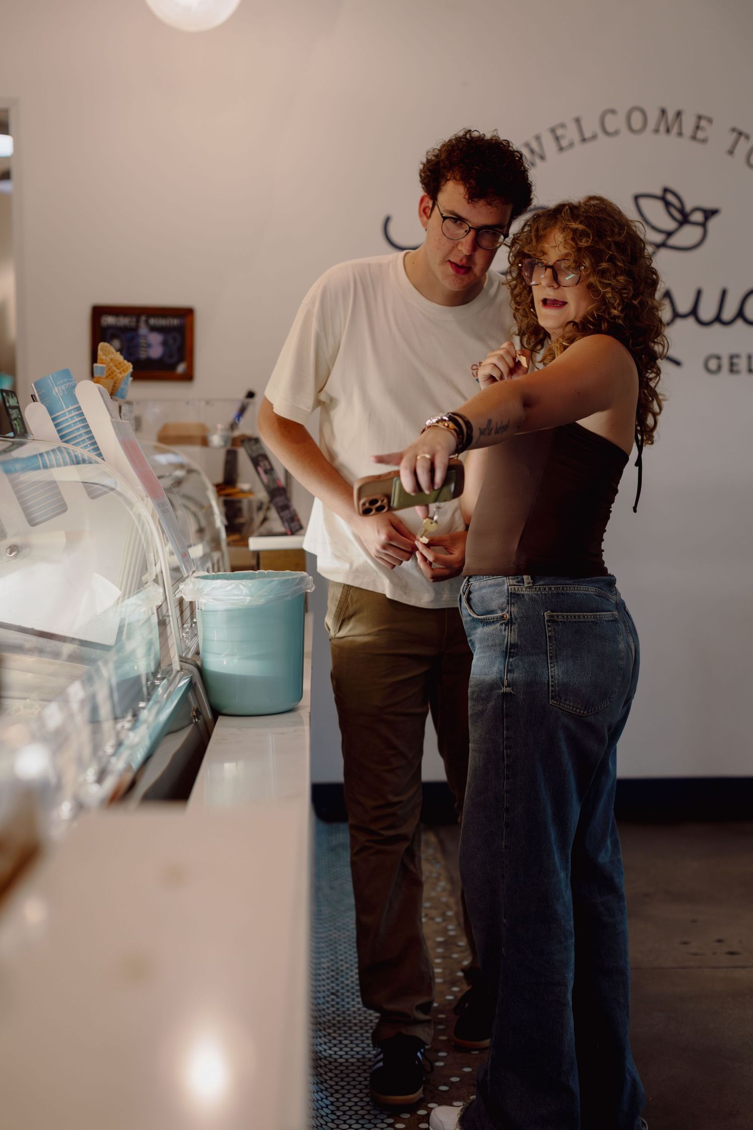 Couple looking at gelato flavors inside a welcoming gelato shop, with display cases along the counter.