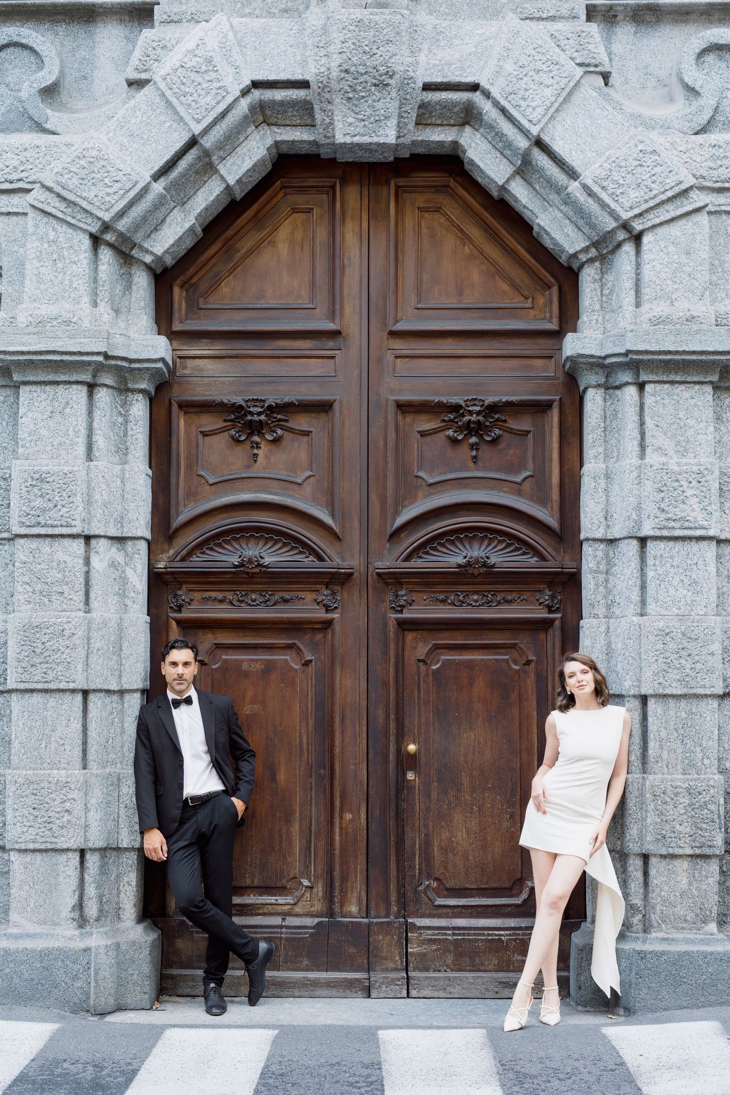A creative wedding photo sequence showing a couple posing playfully in front of an ornate stone church doorway. Milan, Italy. Bridal. luxury