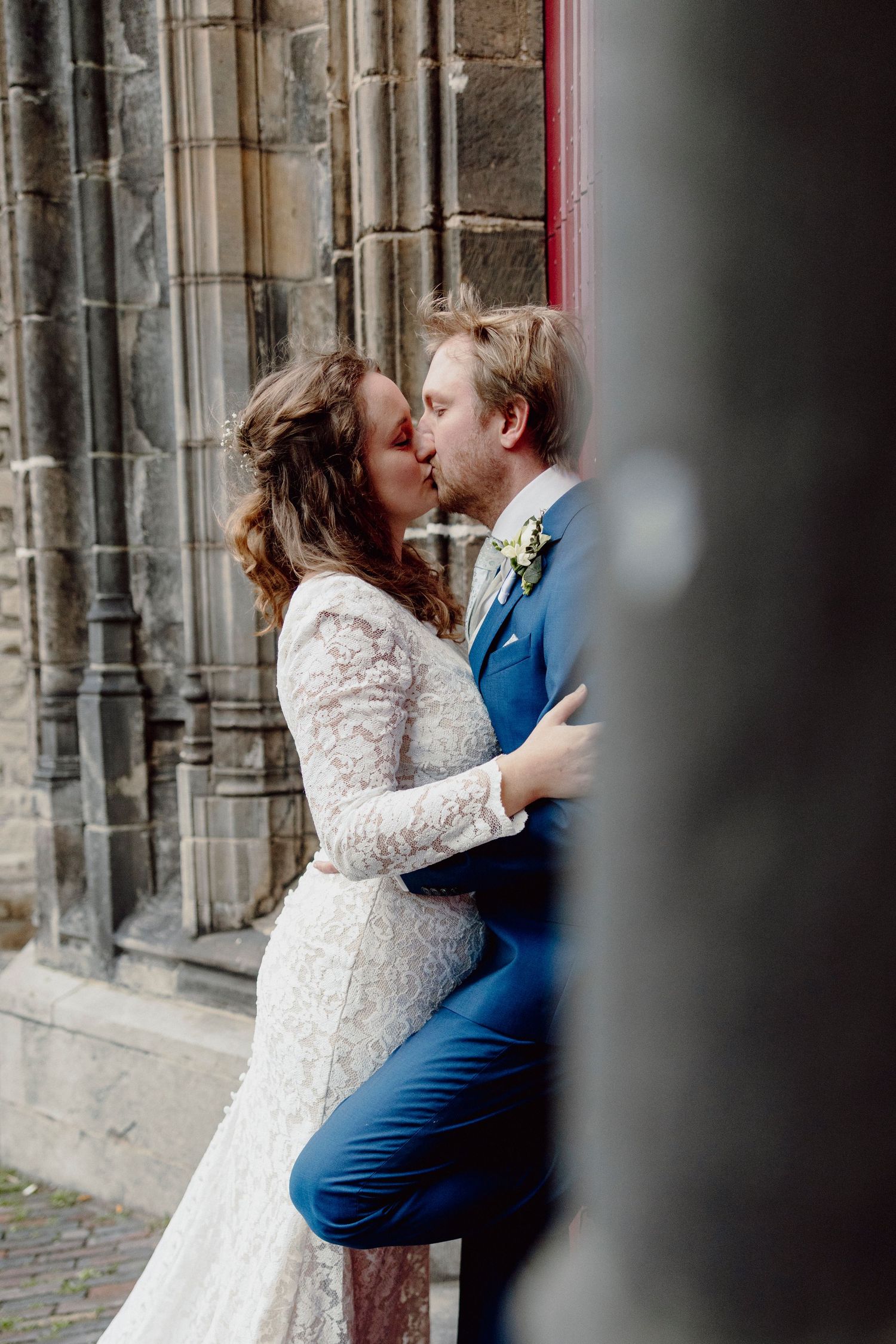 Intimate wedding moment captured between stone pillars with classic architectural details.