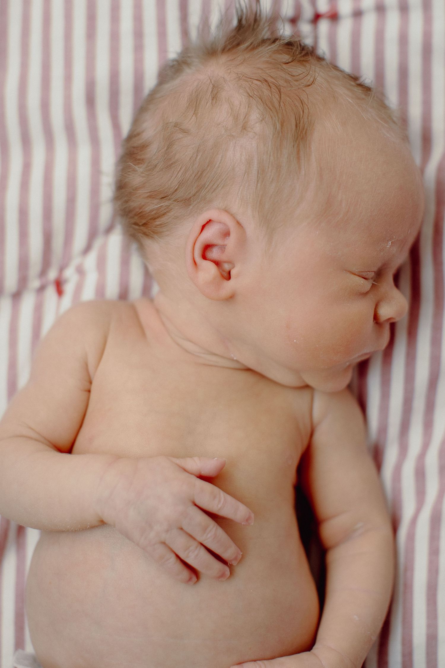 A sleeping baby lies on striped bedding in a series of peaceful poses showing different angles of rest.