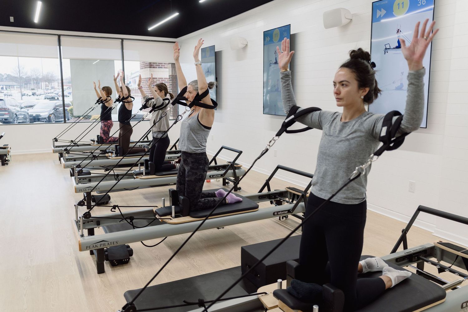 People exercising on treadmills in a bright, modern fitness facility with large windows.