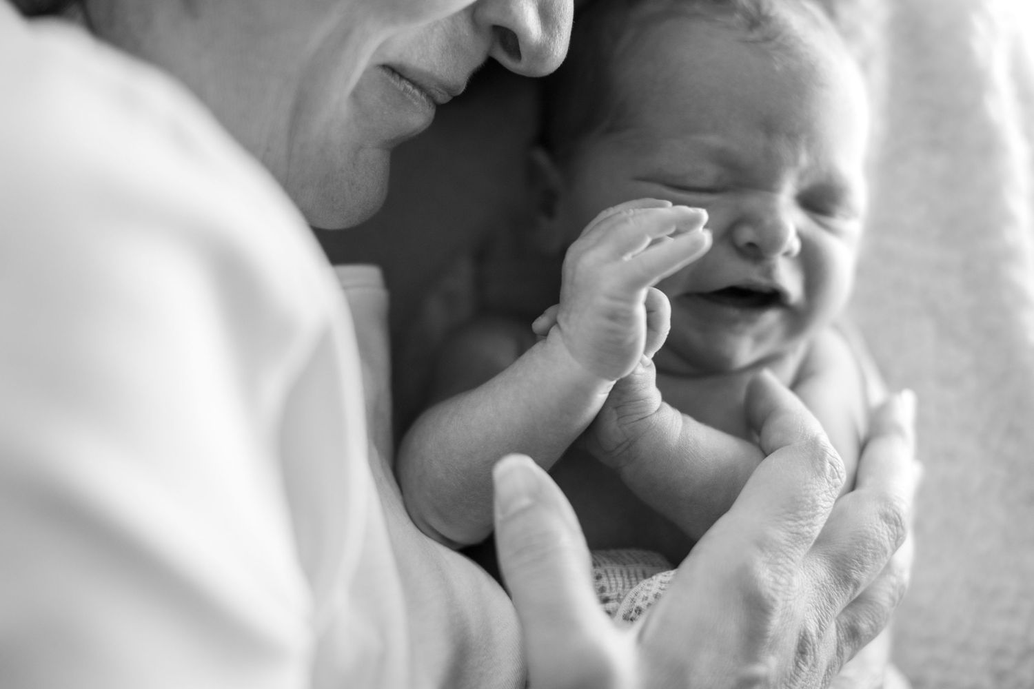 A close-up black and white photo showing an infant's face with a gentle smile and peaceful expression.