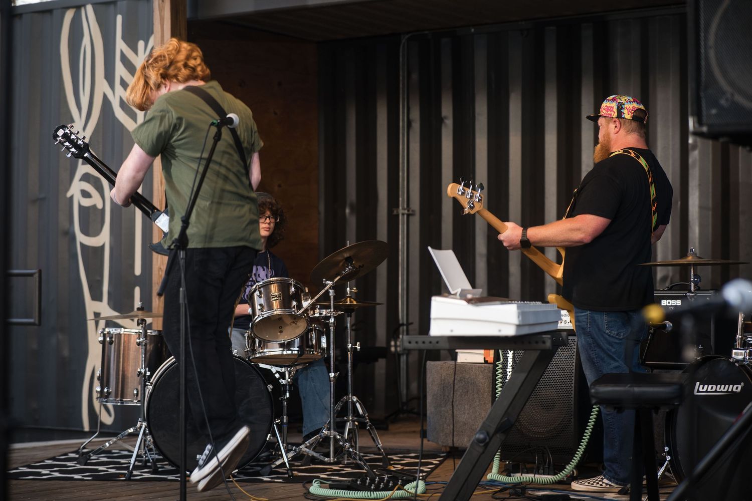 Musicians perform on stage with instruments and microphones during a live concert performance.
