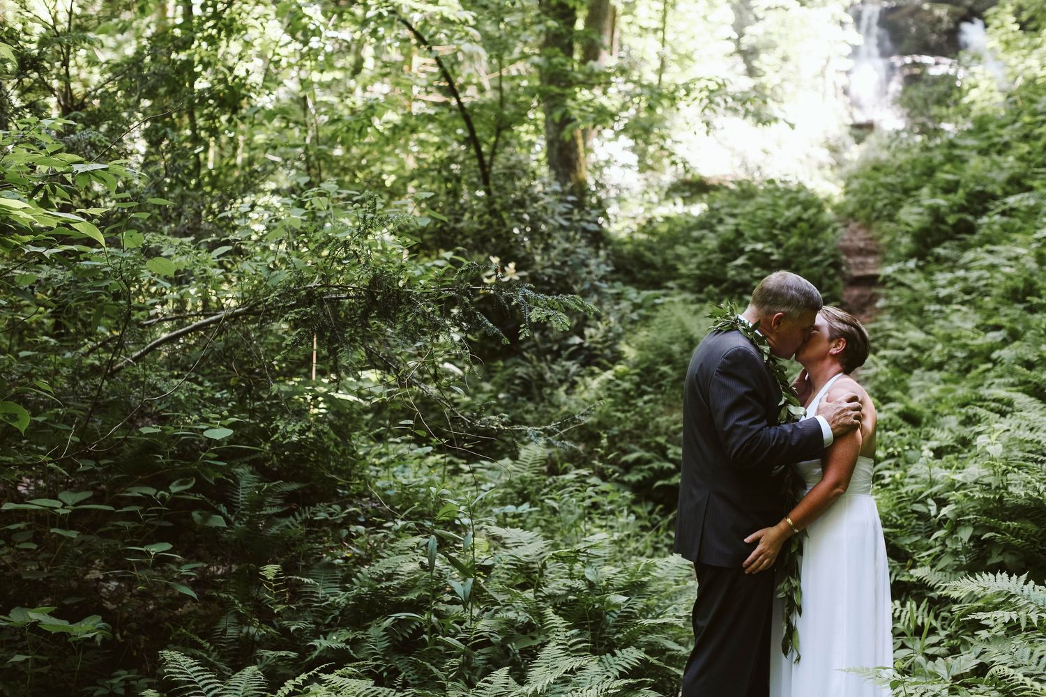 A wedding celebration unfolds on a scenic woodland path surrounded by lush vegetation.