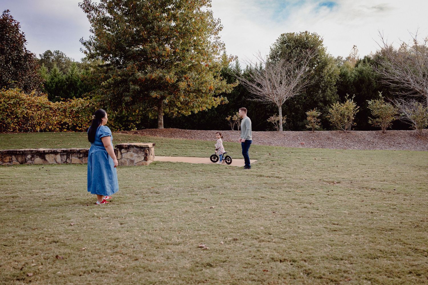 People enjoying a sunny autumn day in a grassy park with trees in the background.