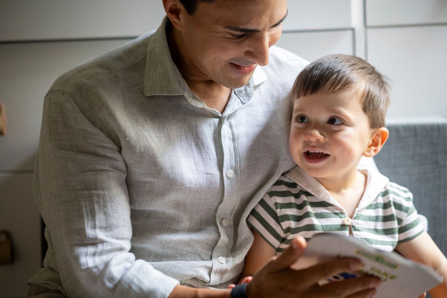 Parent and child share a joyful moment together while sitting on a couch.