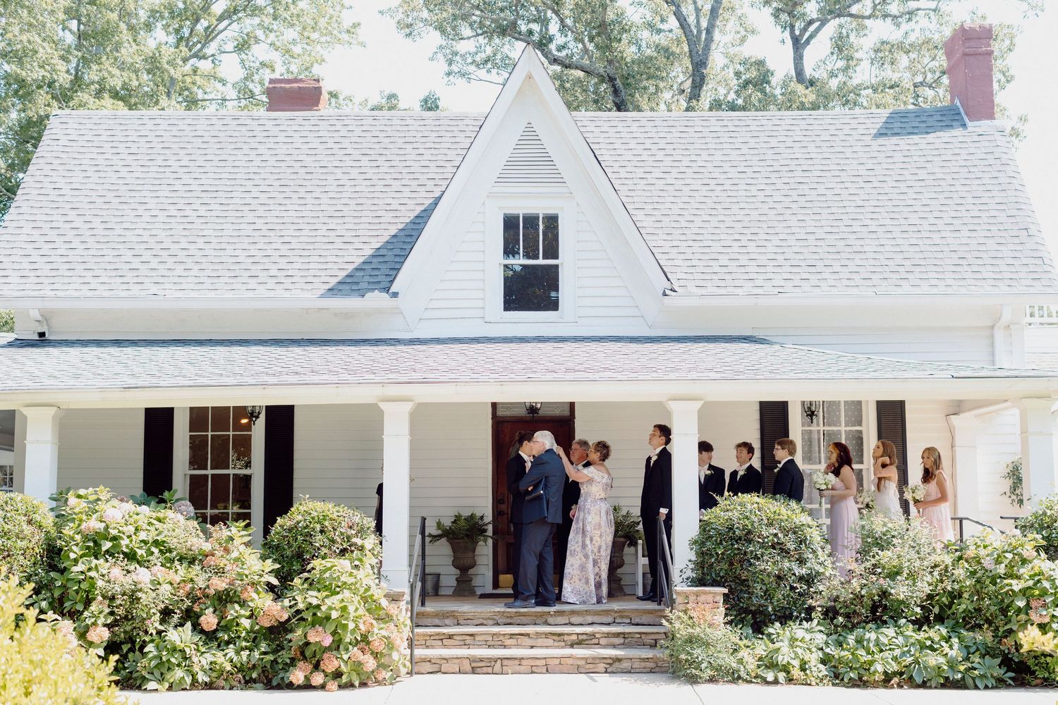 Classic white farmhouse style venue with columned porch decorated for a wedding celebration.