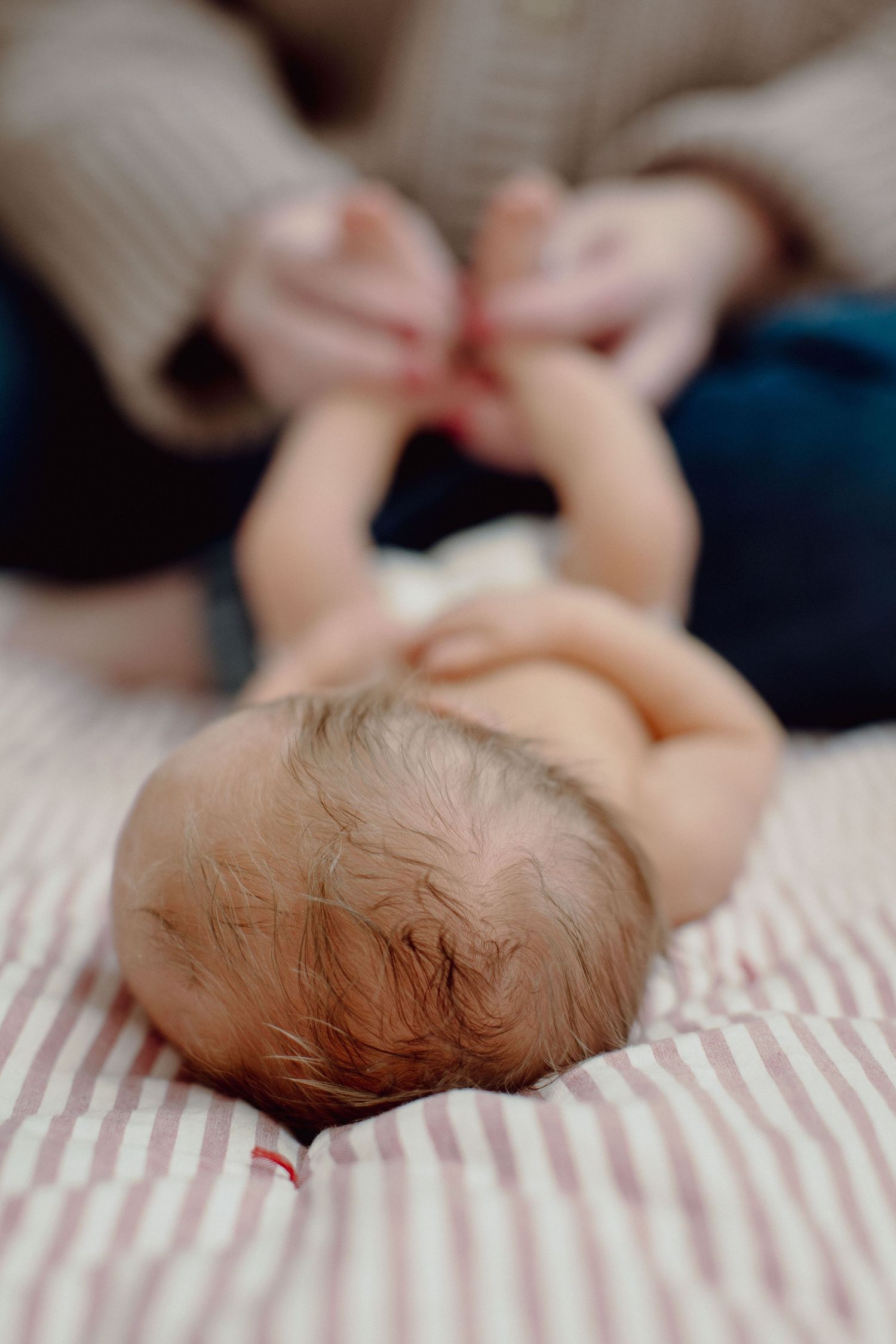 Close-up view of a sleeping baby's head resting on red and white striped bedding.