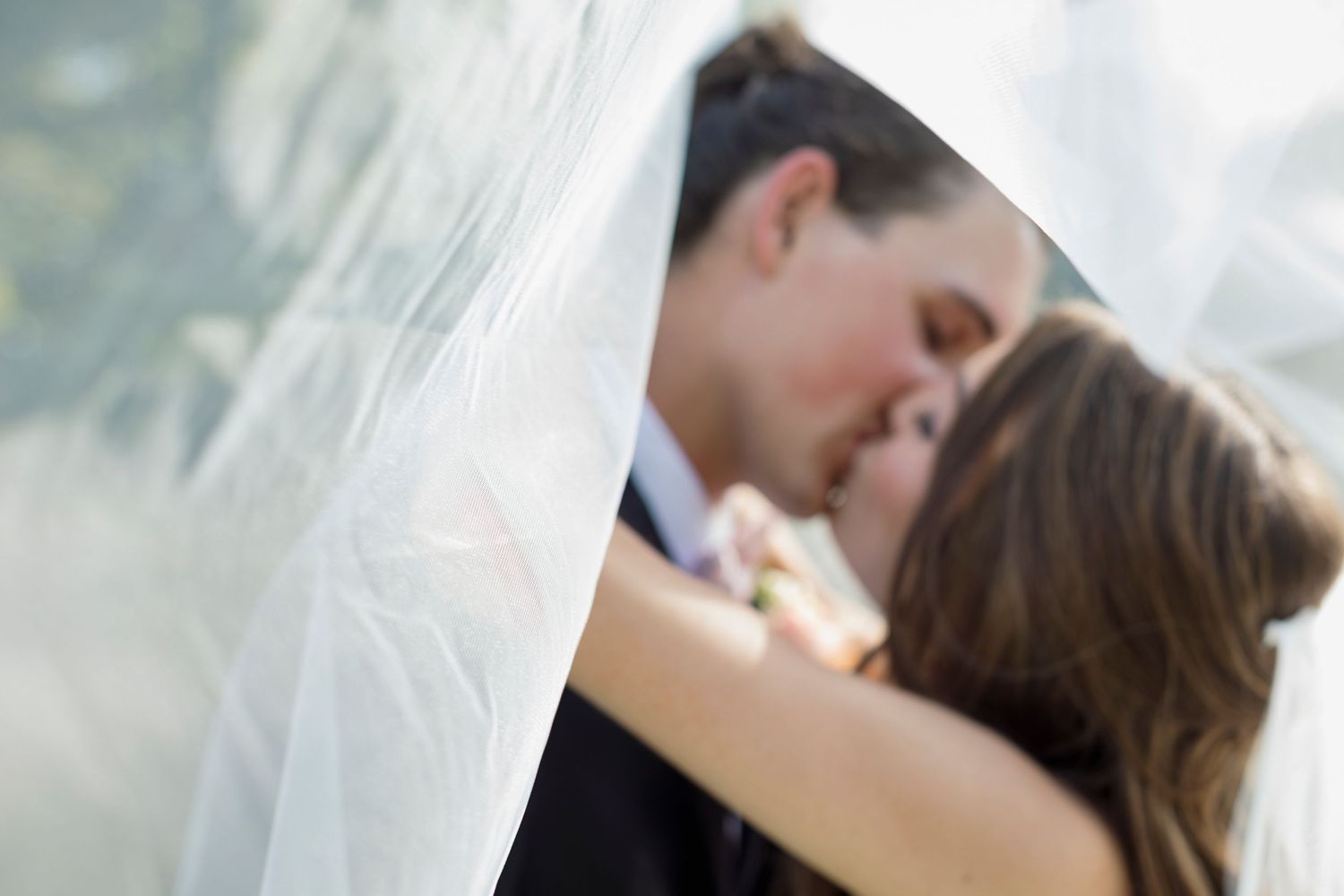 Romantic moment captured between couple under wedding veil.