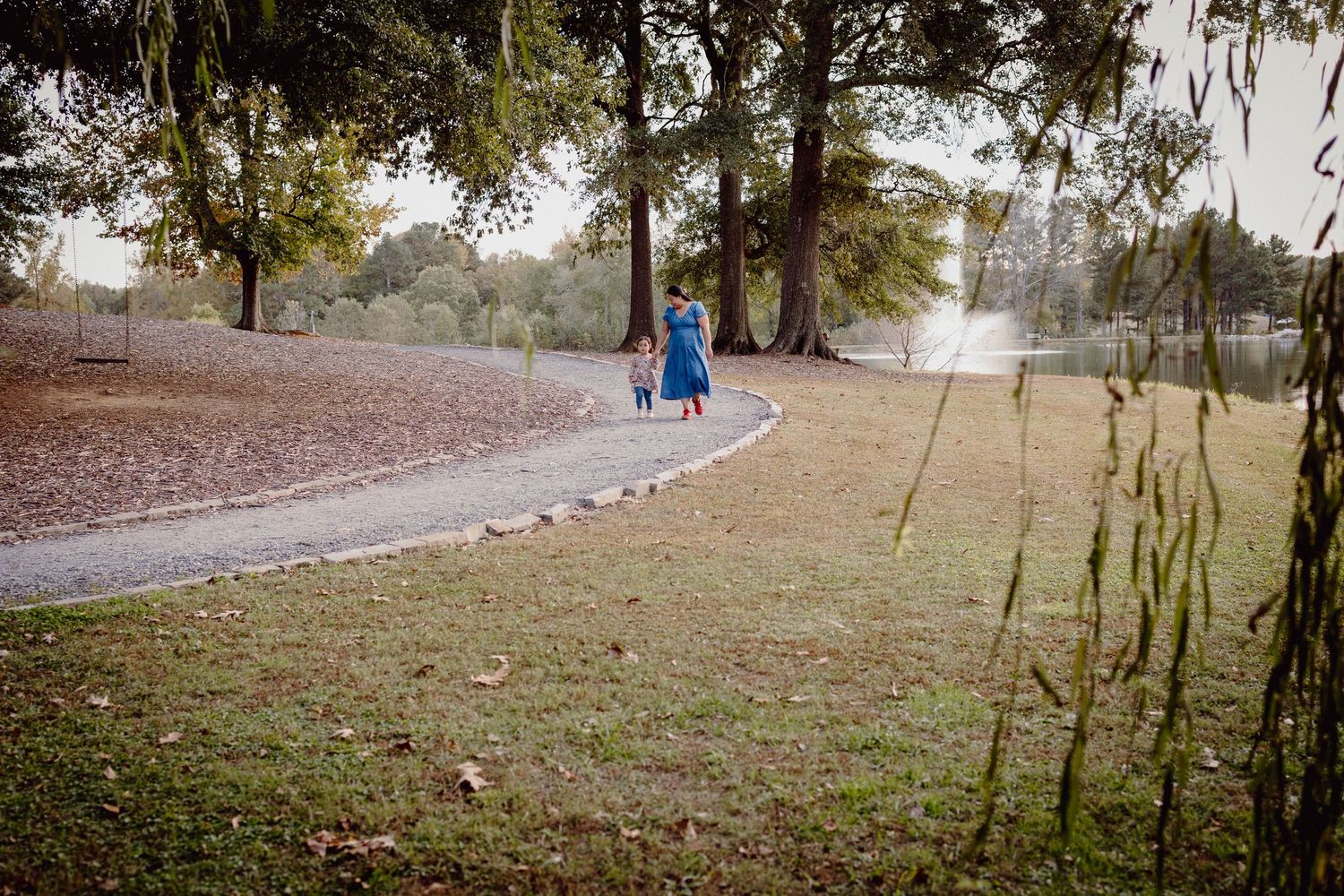 People walking on a curved path through a park on a misty autumn morning.