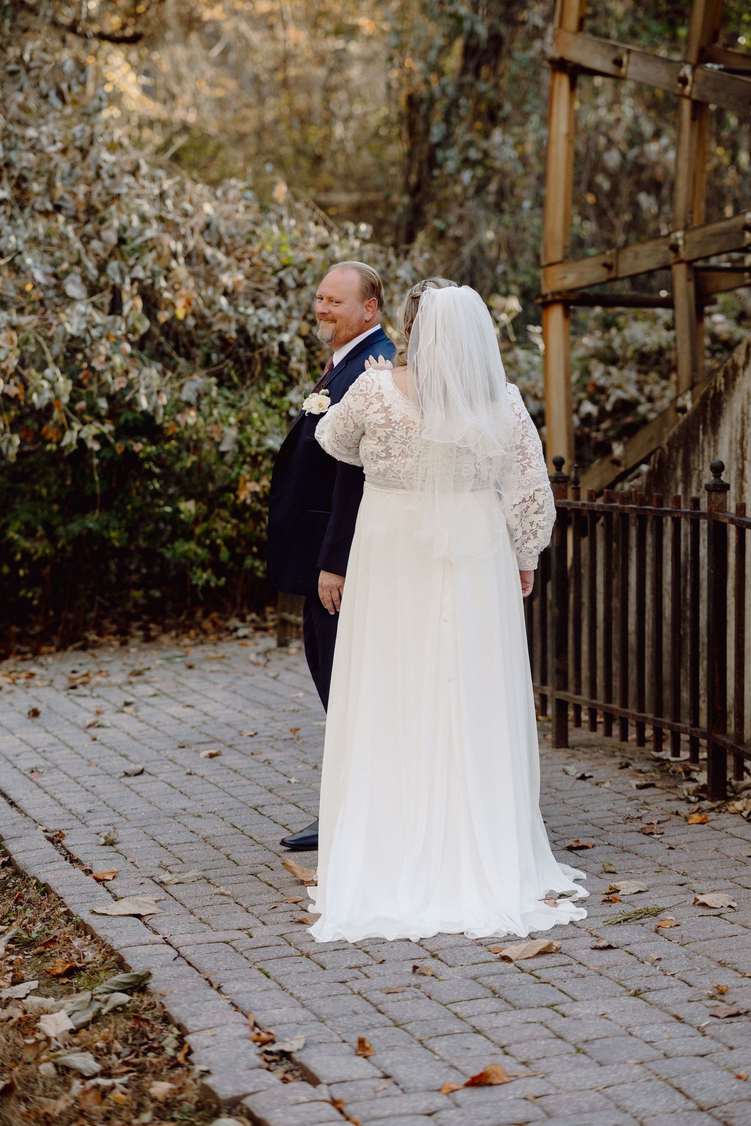 A romantic wedding couple shares intimate moments on a stone path surrounded by autumn foliage.