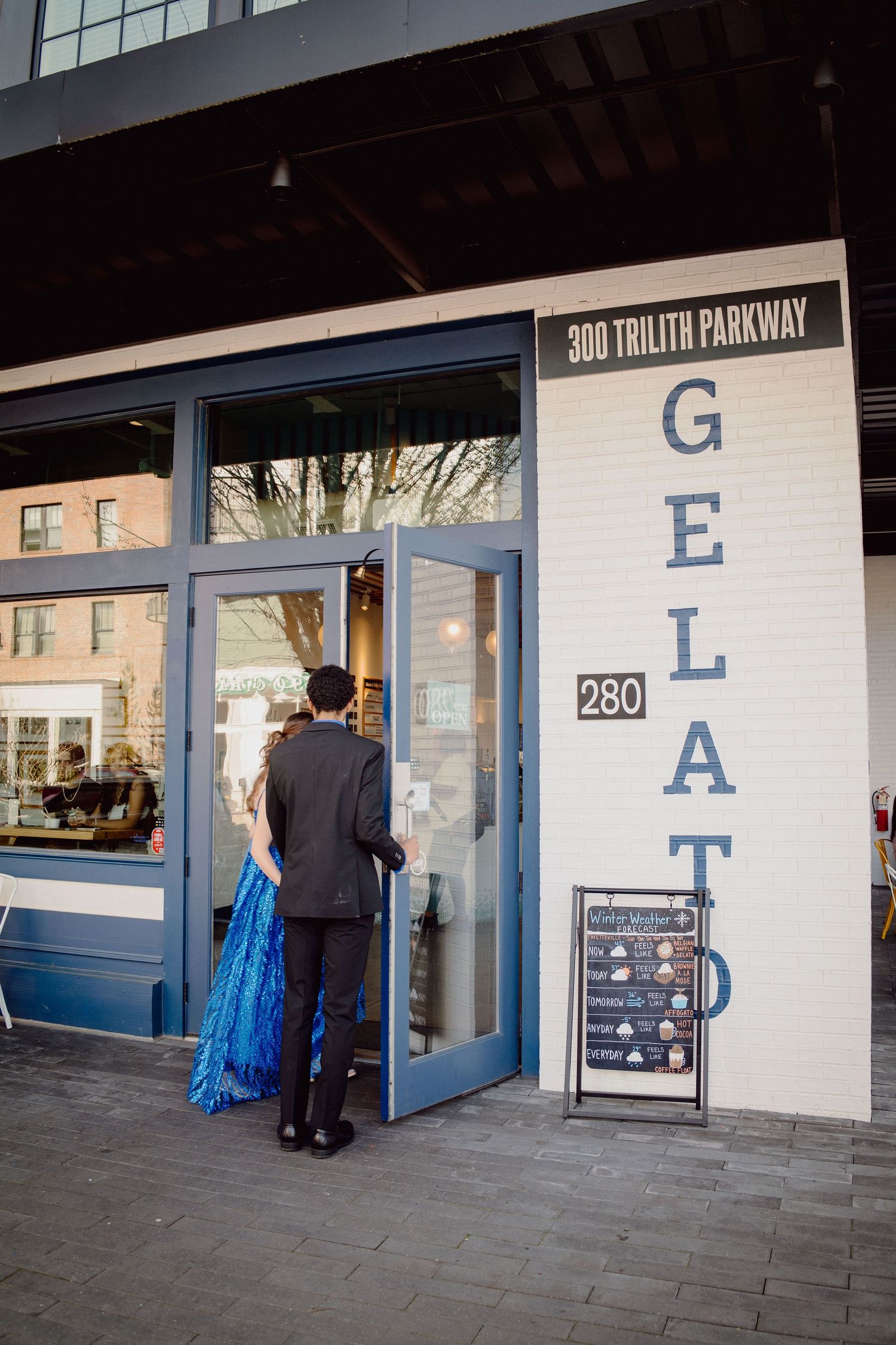 A prom couple enters a gelato shop at 300 Trilith Parkway, the woman wearing a stunning blue sequined gown.