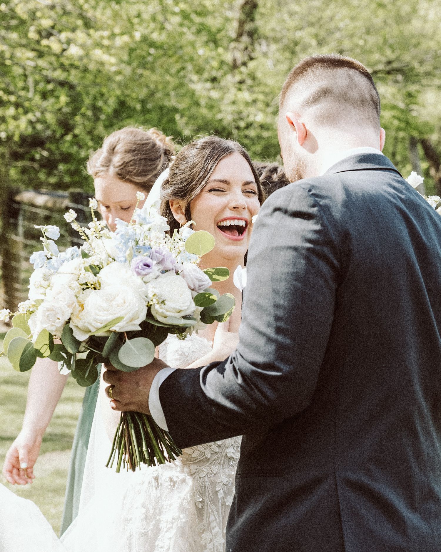 Candid wedding moment showing joyful laughter with white floral bouquet.