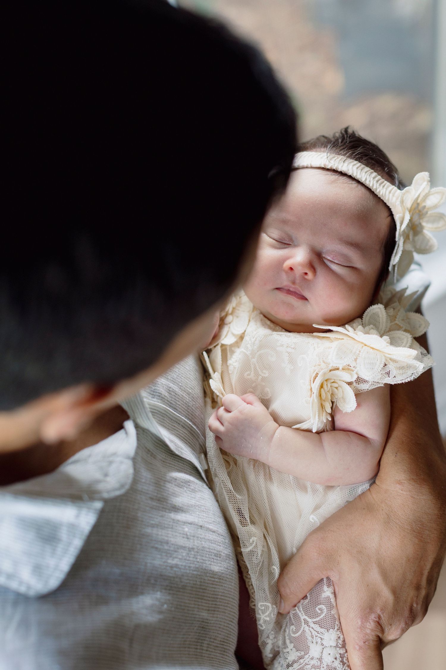 A sleeping baby in white lace clothing lies peacefully on a soft surface.