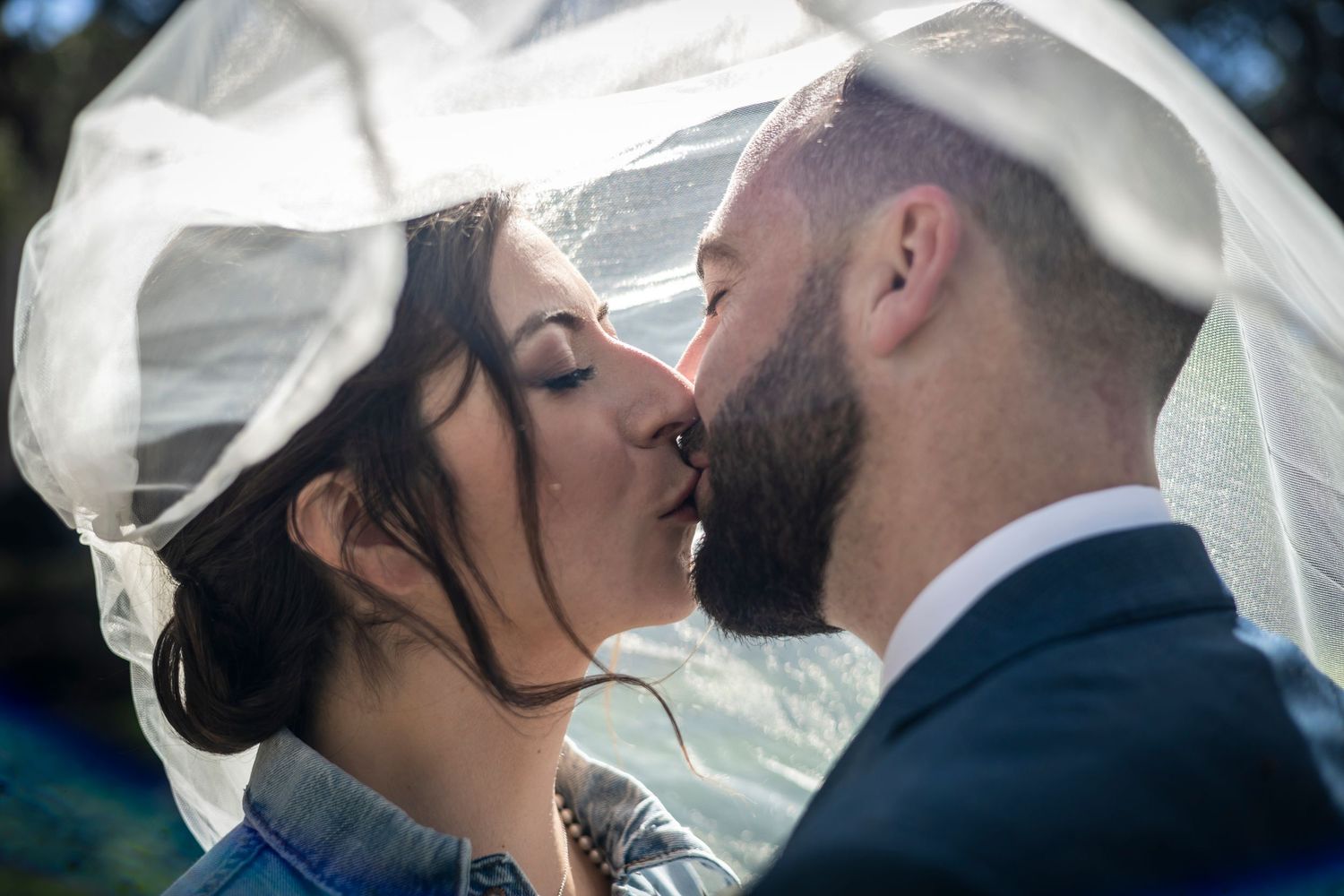 Romantic wedding portraits with flowing veil in natural outdoor lighting.