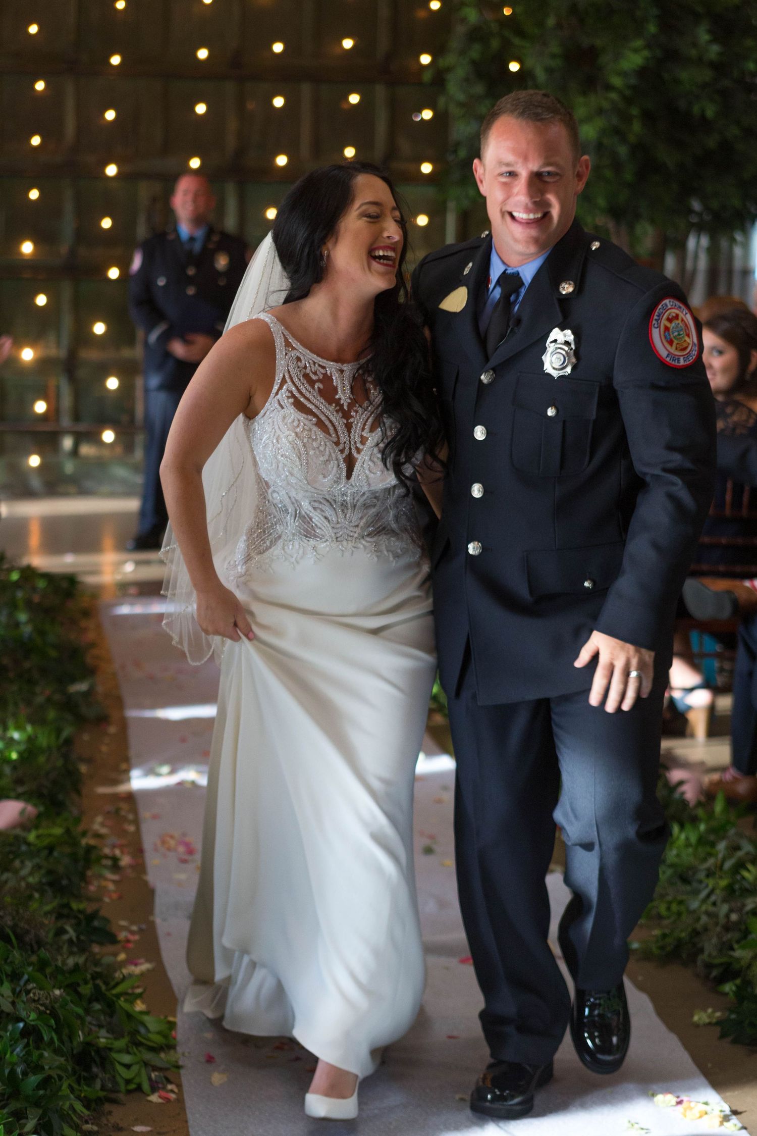 A couple dances and laughs together at their wedding reception under string lights.