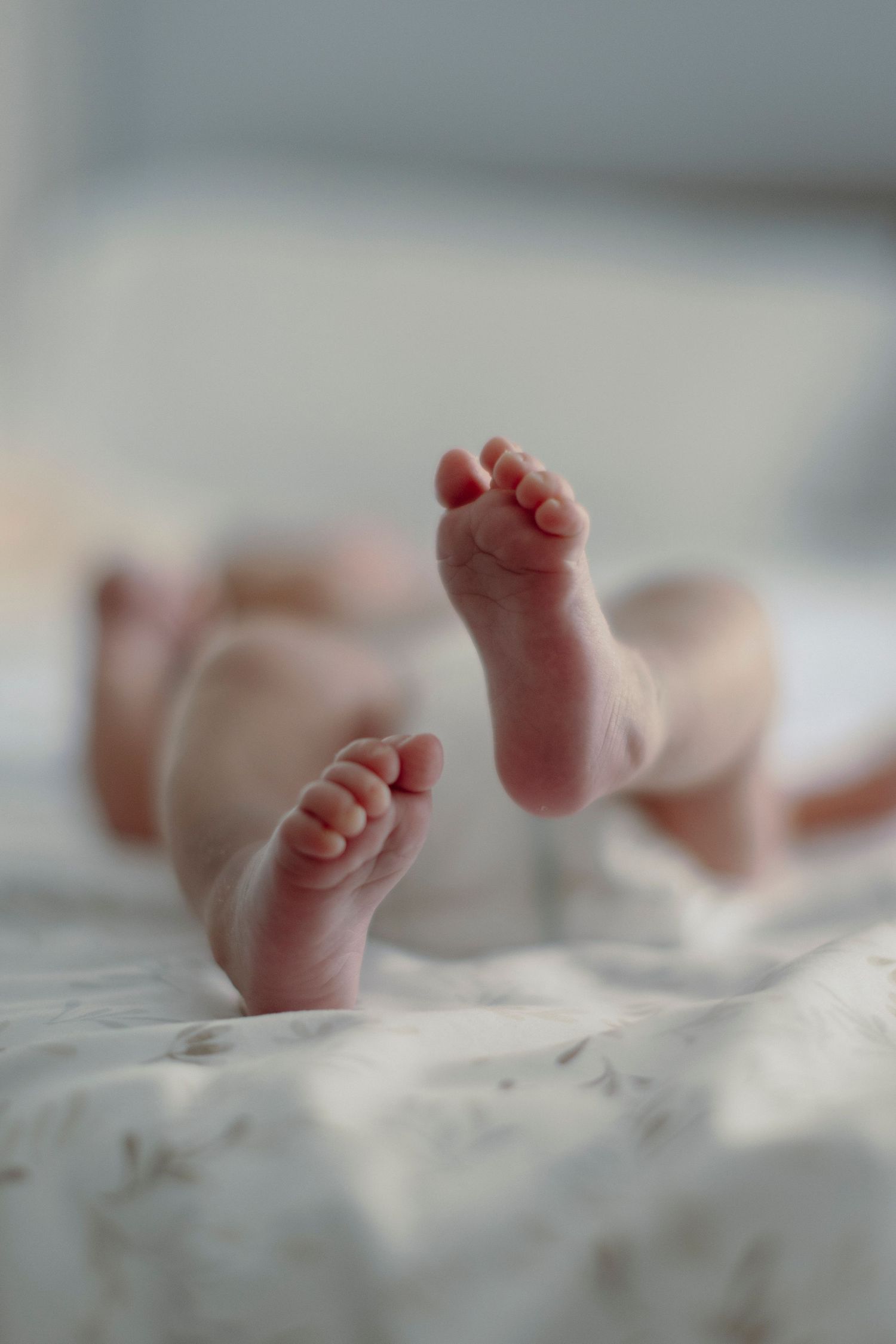 Tiny baby feet resting on soft white blankets in a series of close-up photos.