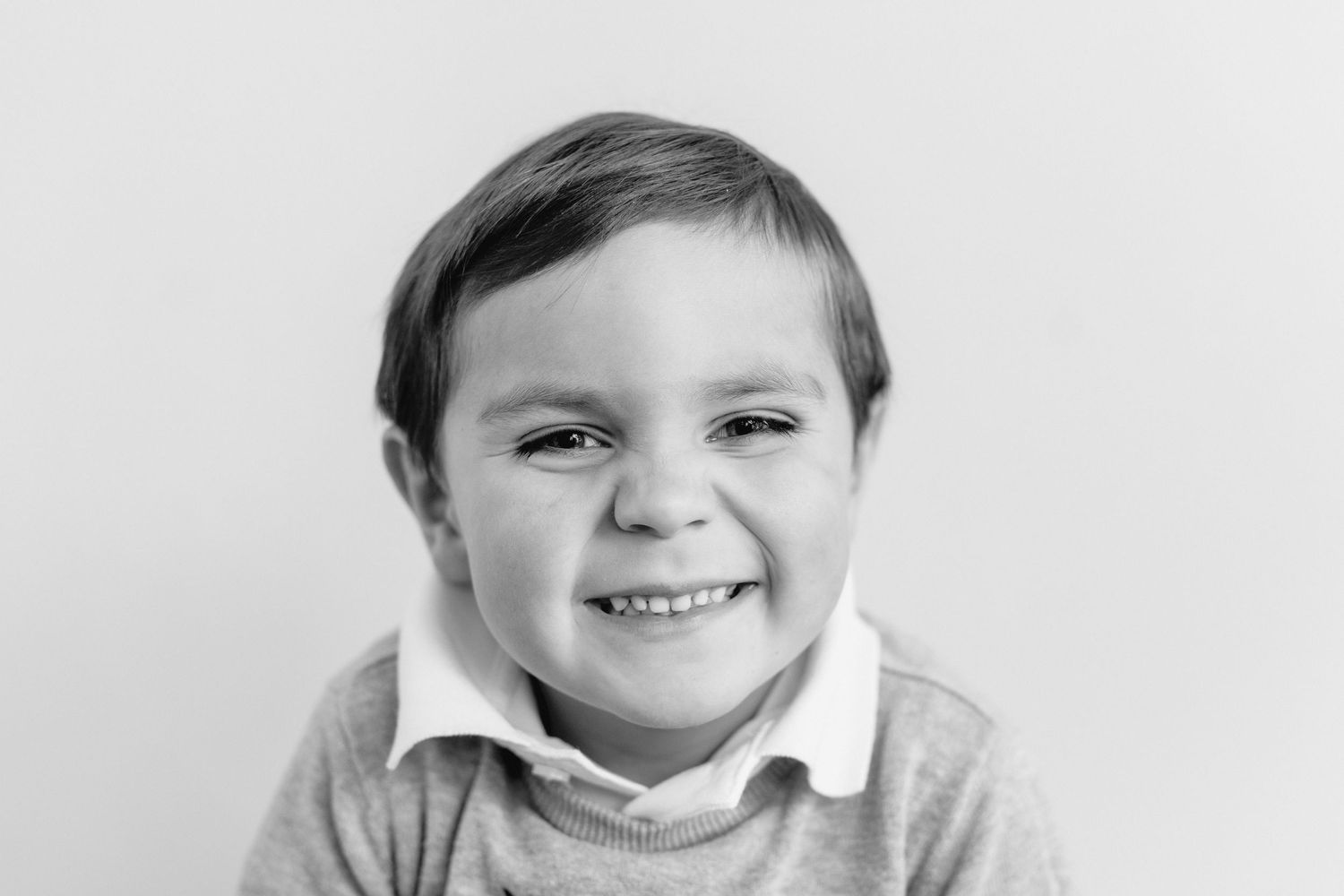 A black and white collage of four close-up portraits showing joyful expressions and bright smiles.
