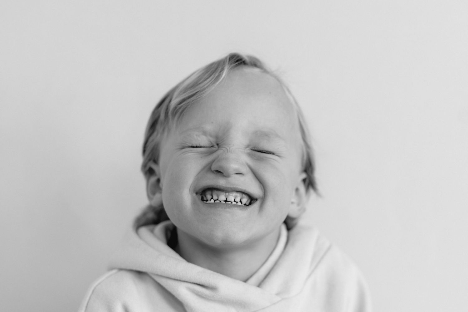 A series of black and white portraits showing joyful expressions and genuine laughter.