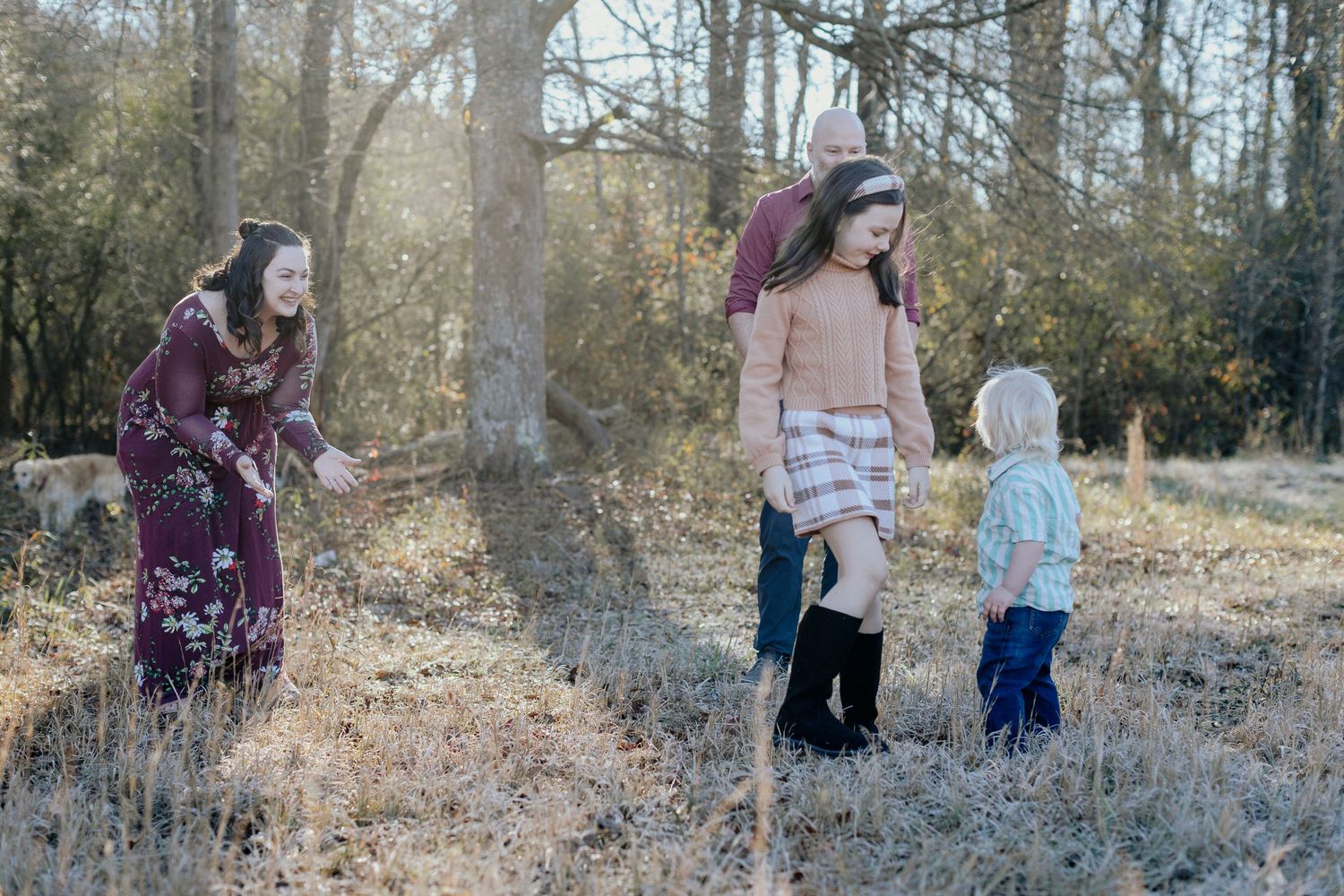 A group walks together through a frosty winter field with bare trees in the background on a sunny morning.