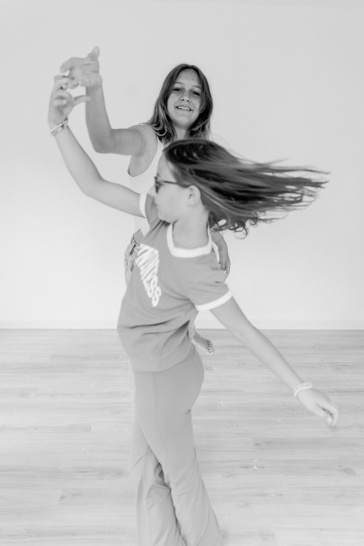 A series of black and white photos showing someone dancing joyfully in casual athletic wear.
