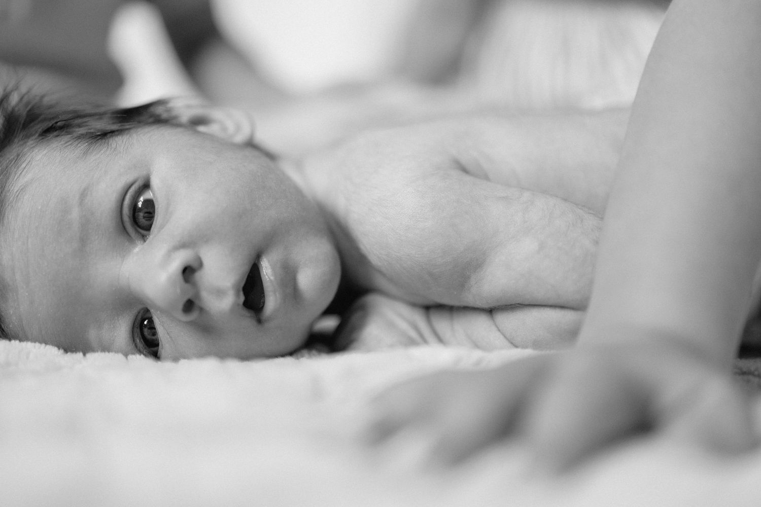Black and white artistic portrait series showing close up views of a person resting on white bedding.