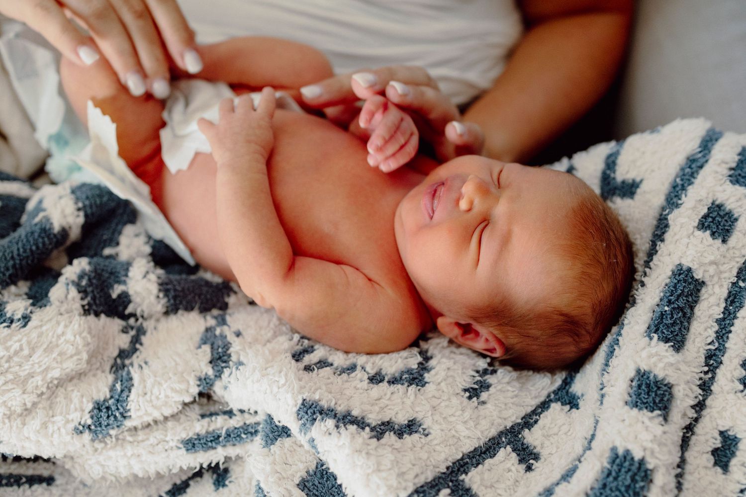 Newborn baby sleeping peacefully on a patterned blanket with tribal designs.