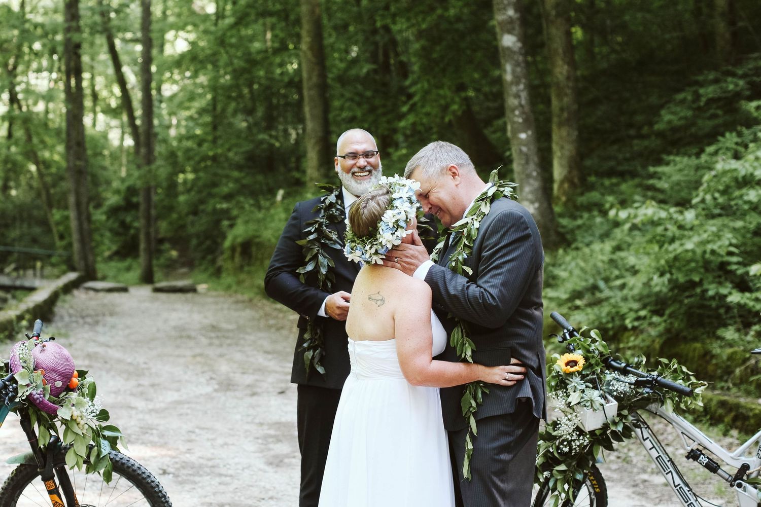 An intimate wedding ceremony taking place on a forest path surrounded by greenery.