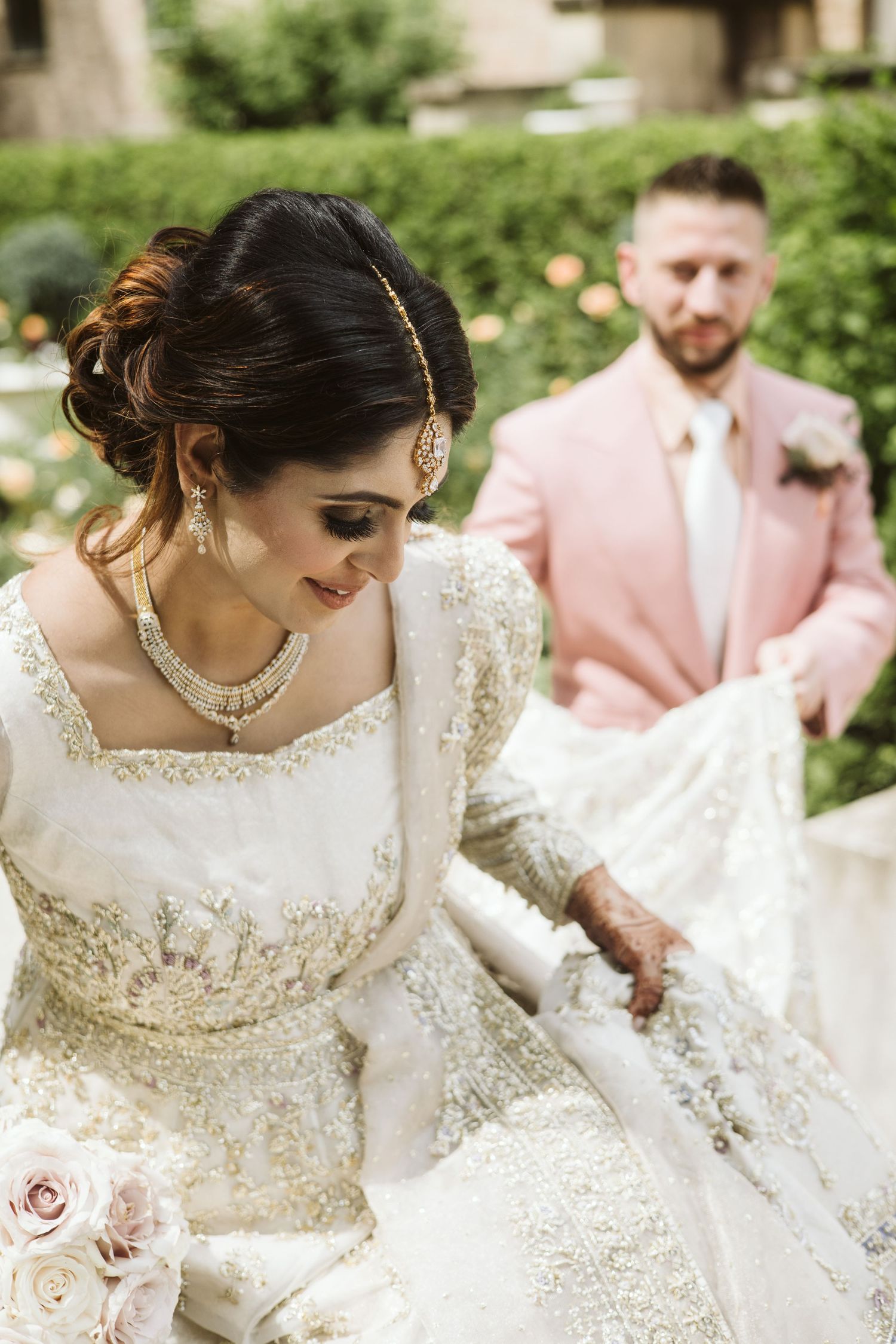 Wedding party in pastel pink and white attire gathered outdoors.