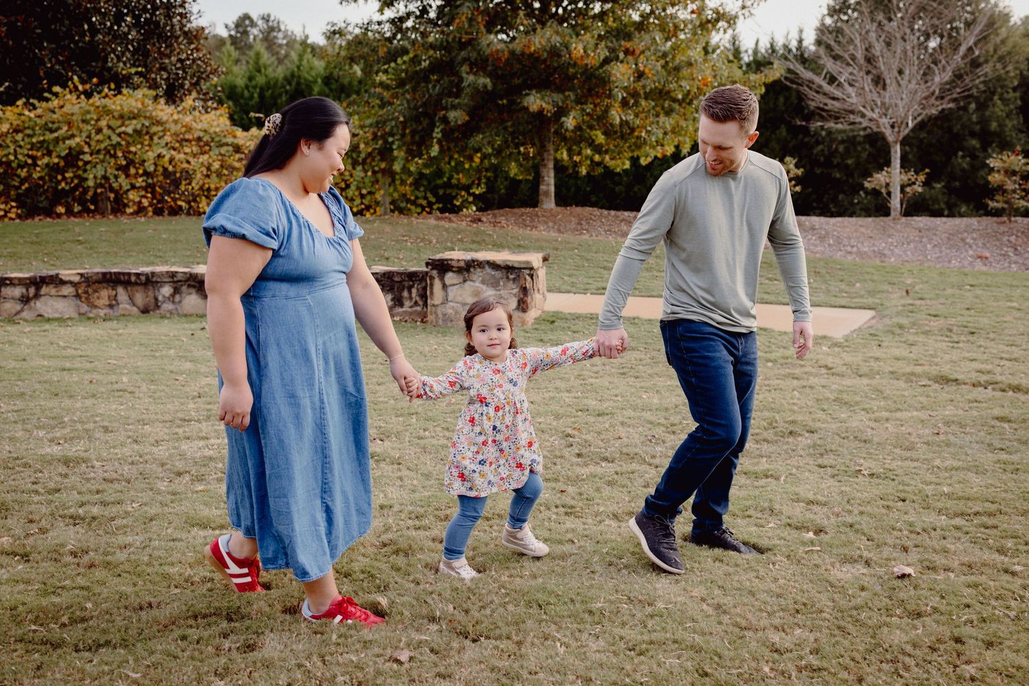Family plays together in a grassy field during a golden sunset photo session.