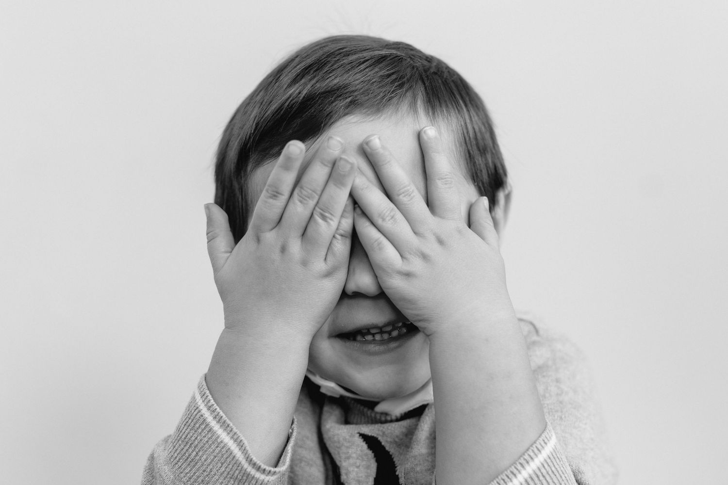 A person in a black and white photo holds their head in their hands in a gesture of frustration or despair.