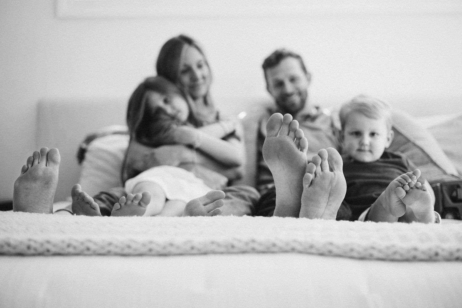 A series of black and white photographs showing intimate moments of people relaxing together in bed.