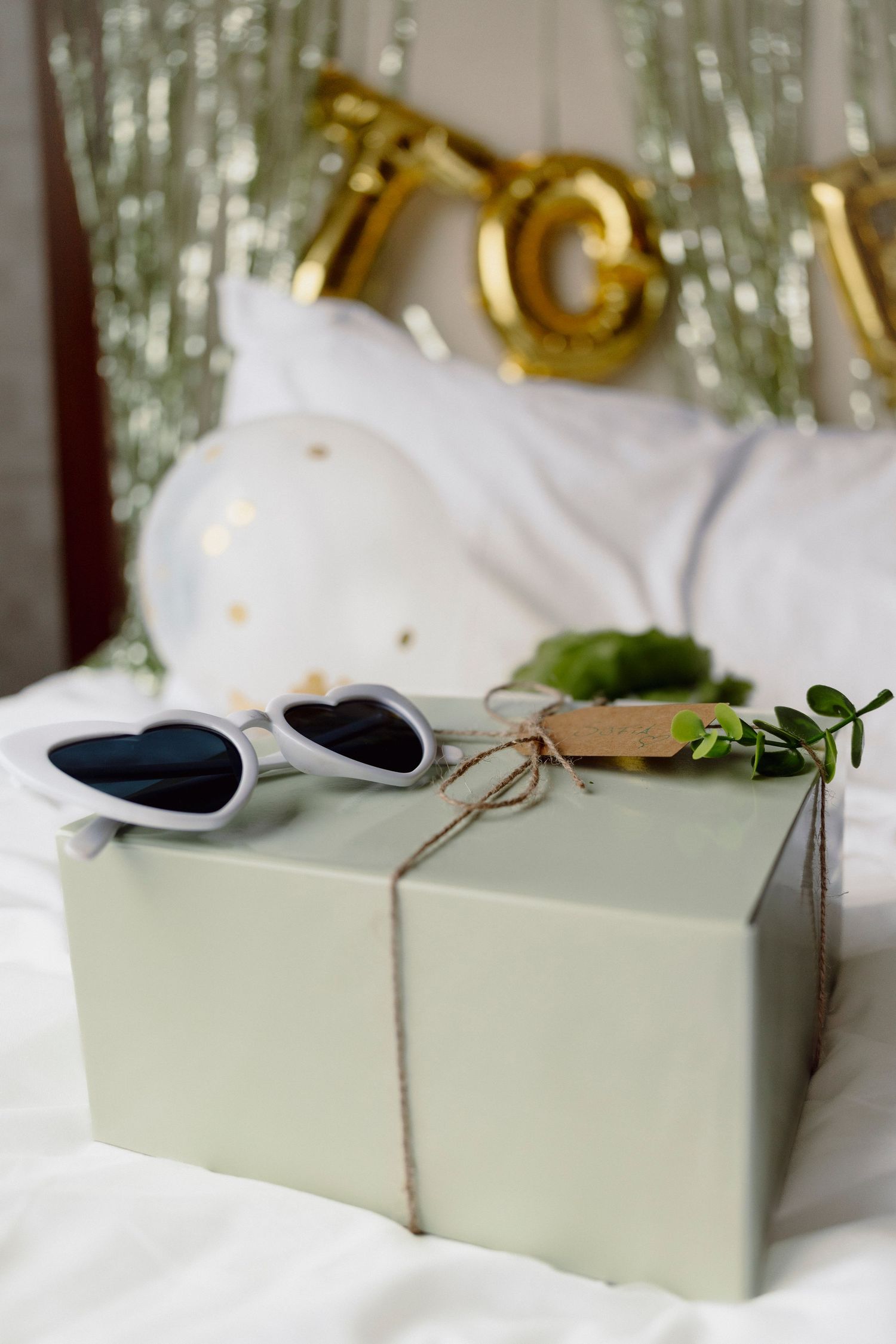 Mint green gift box with string tied around it on white surface with gold decorations.